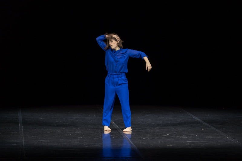 Martina Gambardella in una tuta blu elettrico, a piedi scalzi, mentre prova Error.  È in piedi, con le gambe leggermente divaricate, un braccio sollevato lateralmente e l'altro sul capo.
