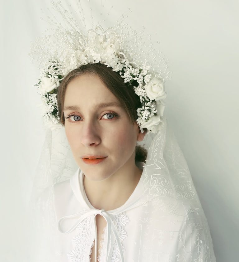 Una ragazza in primo piano con fiori in testa bianchi e velo