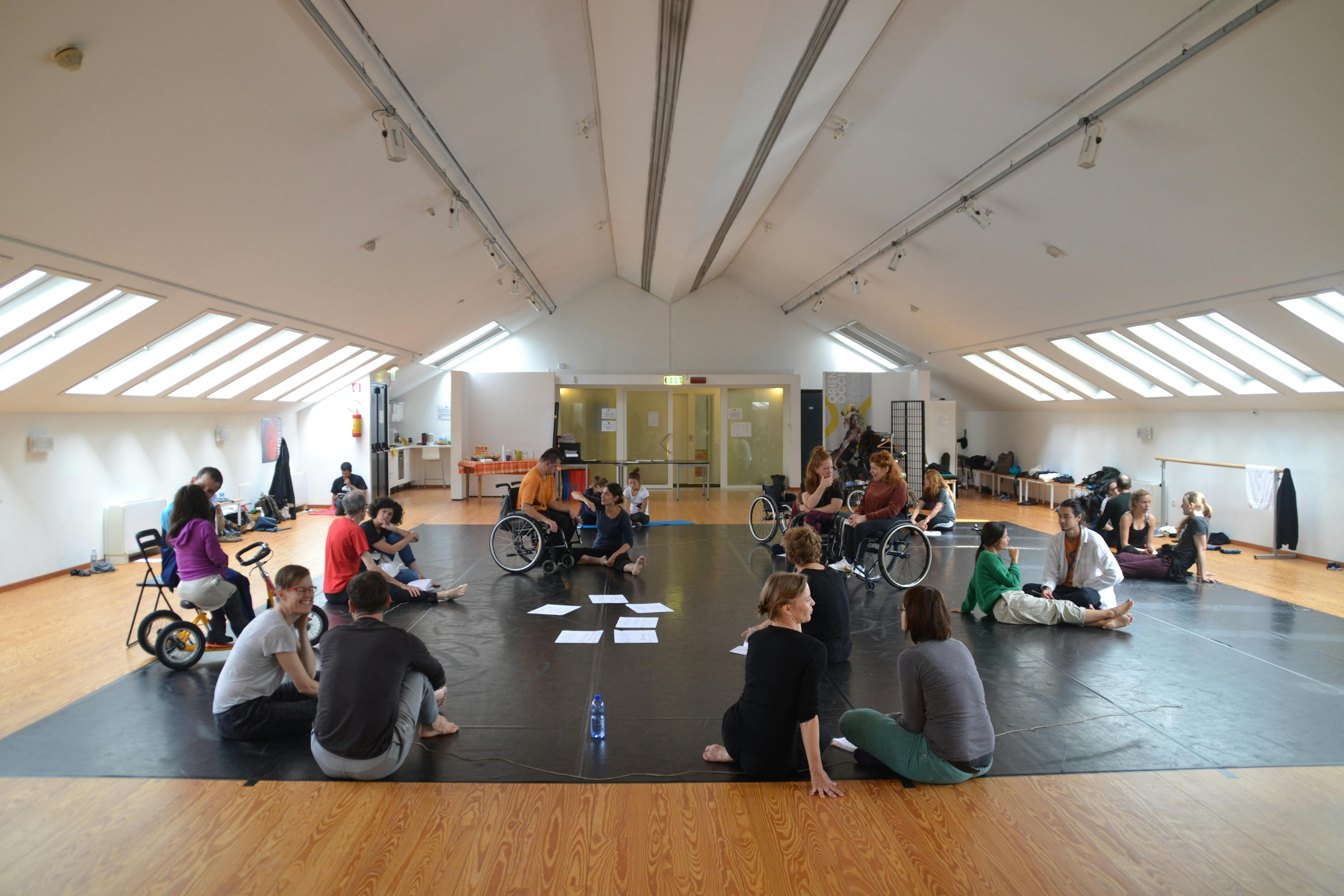 A group of people with and without disabilities discuss in pairs in the Studio of Oriente Occidente during a workshop.