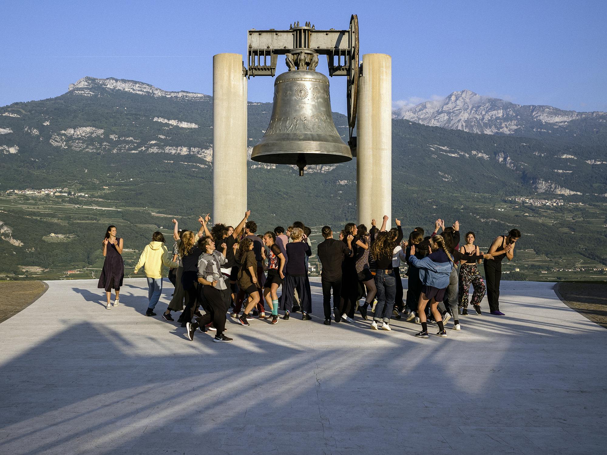 Un gruppo di performer balla all'alba sotto Maria Dolens, la Campana dei Caduti di Rovereto