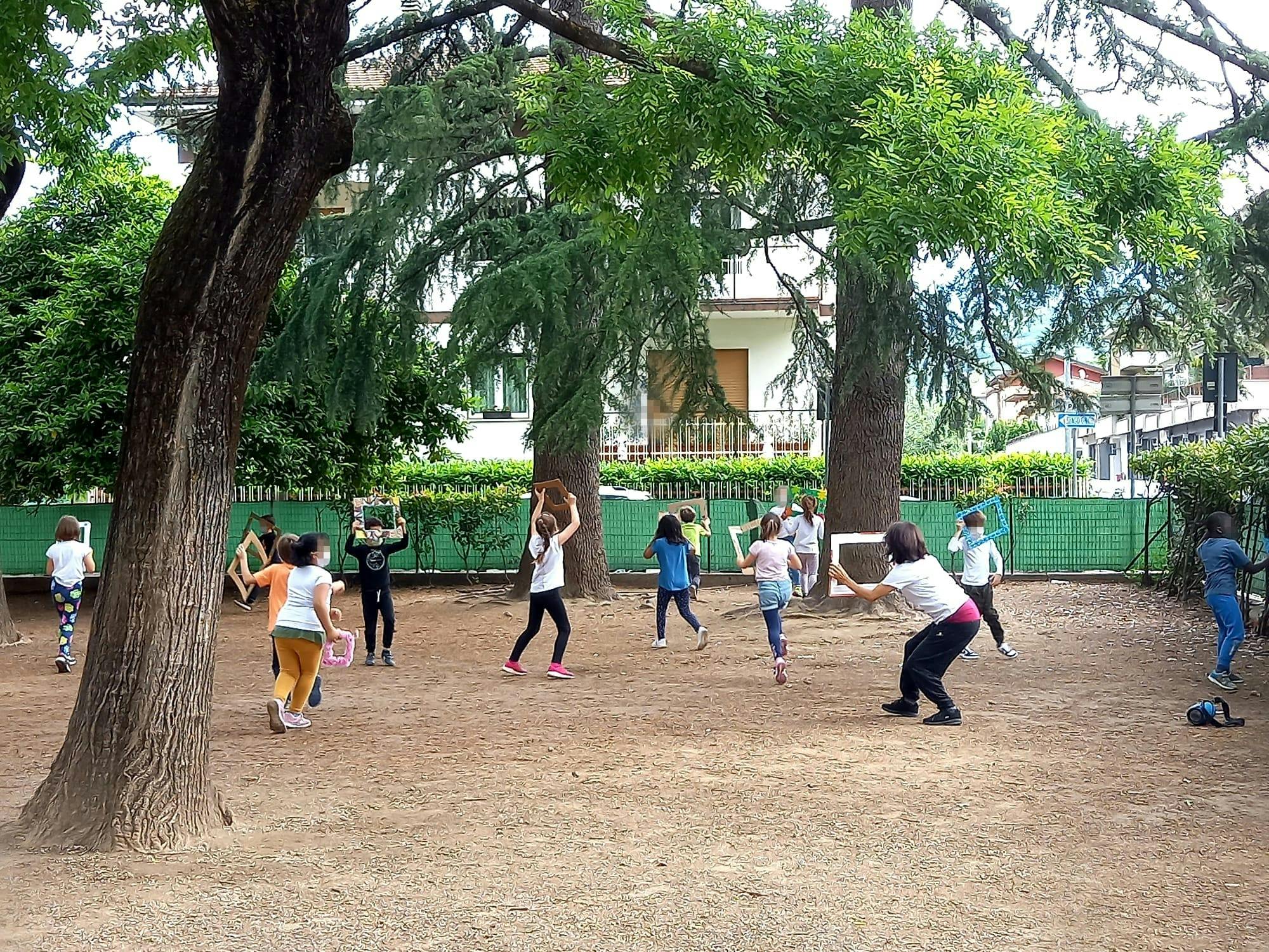 Children run through a courtyard. They hold in their hands empty colored picture frames.