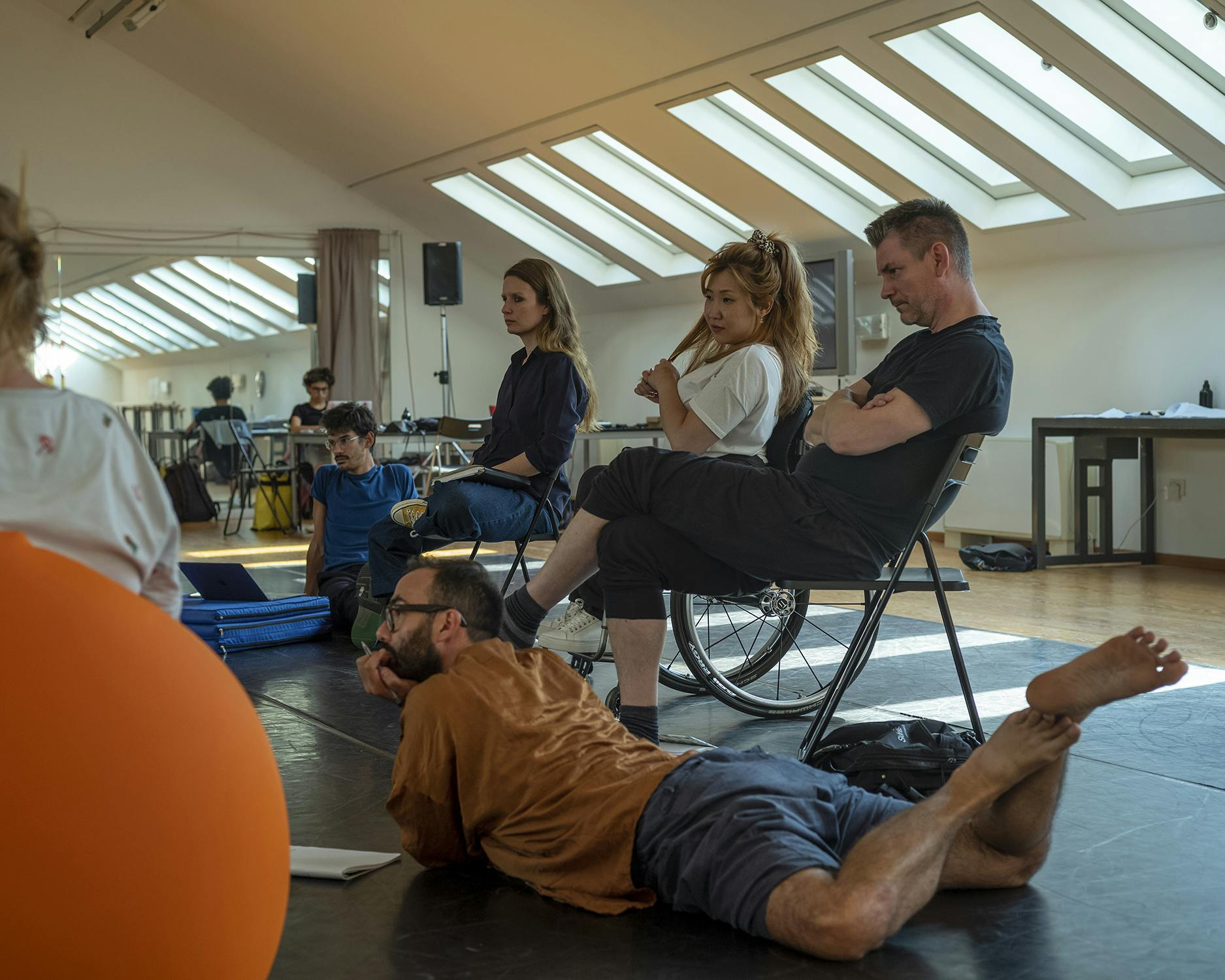 A few EBA workshop participants during a discussion. They are partly lying down, partly sitting in wheelchairs or pouffes depending on different personal needs.