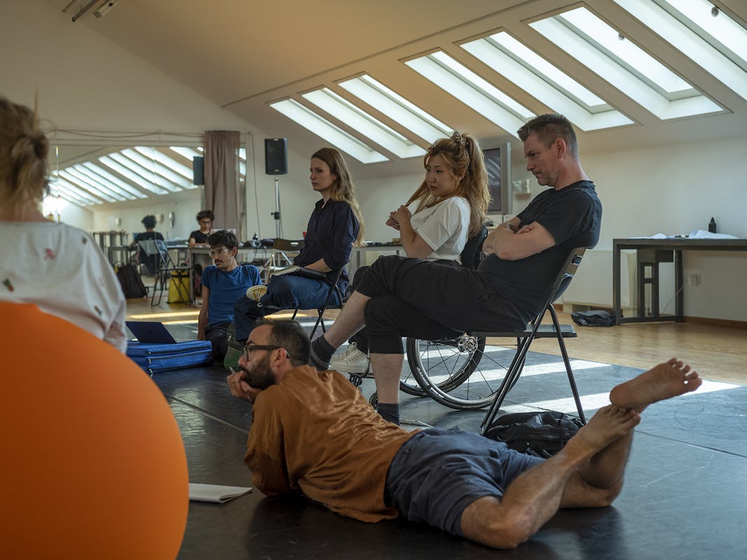 A few EBA workshop participants during a discussion. They are partly lying down, partly sitting in wheelchairs or pouffes depending on different personal needs.