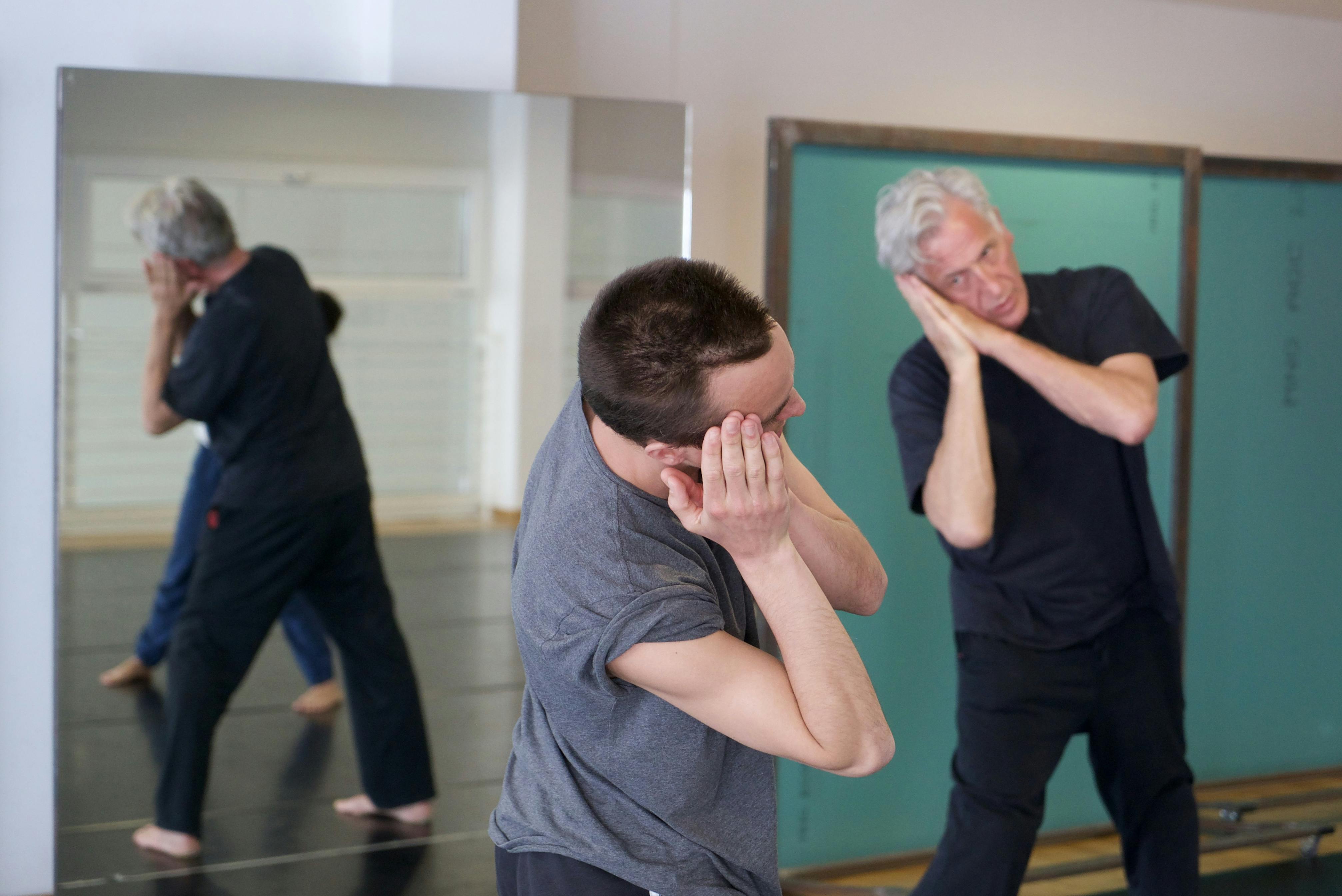 Sindri Runudde rehearsing in the Studio with an older volunteer. Both hold their joined hands resting under their heads in the same direction toward which they shift their weight.