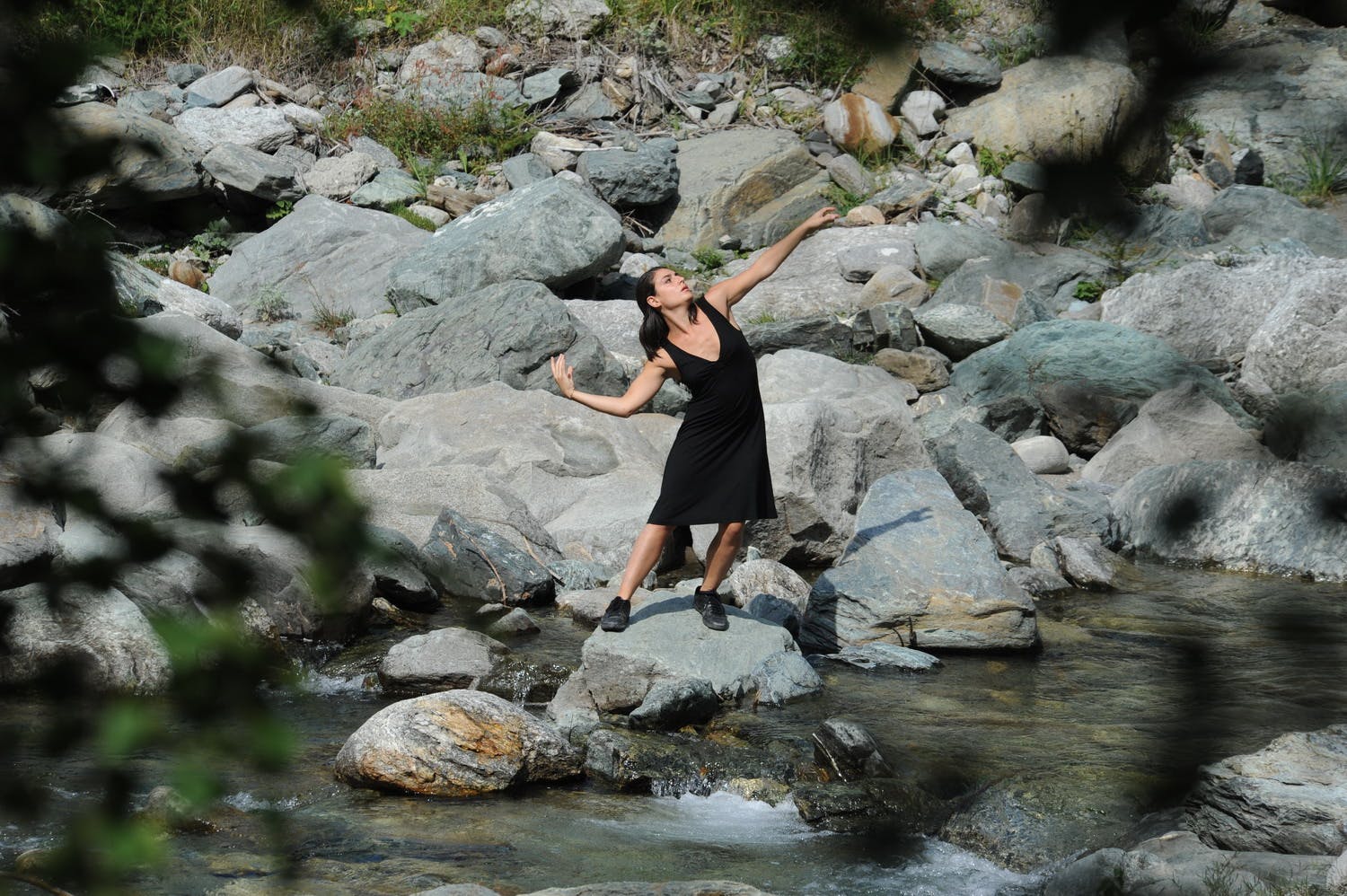 The dancer is standing on a river rock.