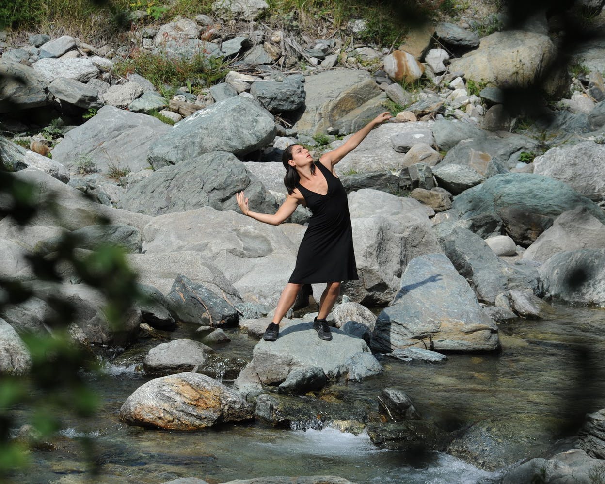 The dancer is standing on a river rock.