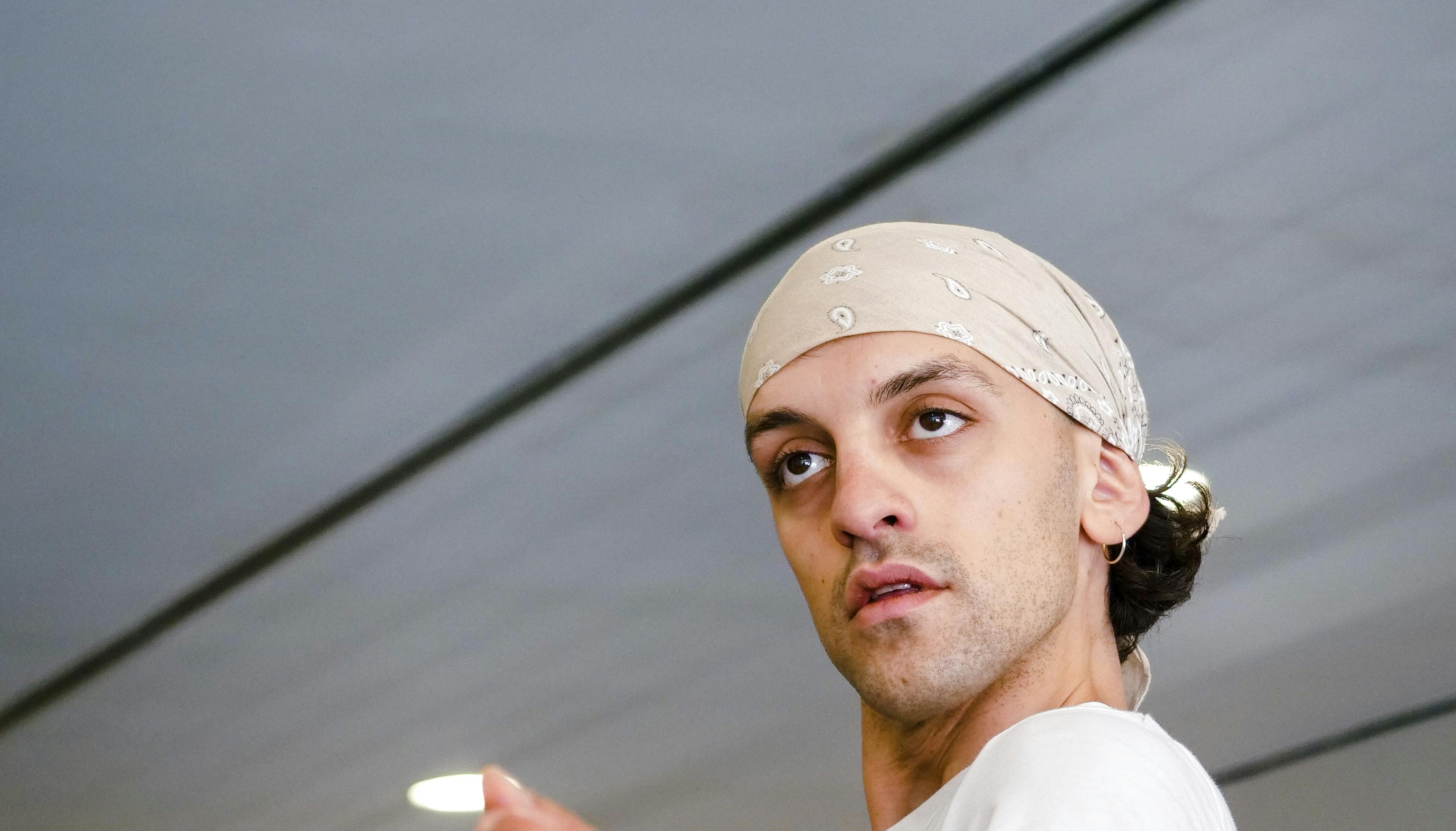 A performer with a beige bandana looks over his forearm 