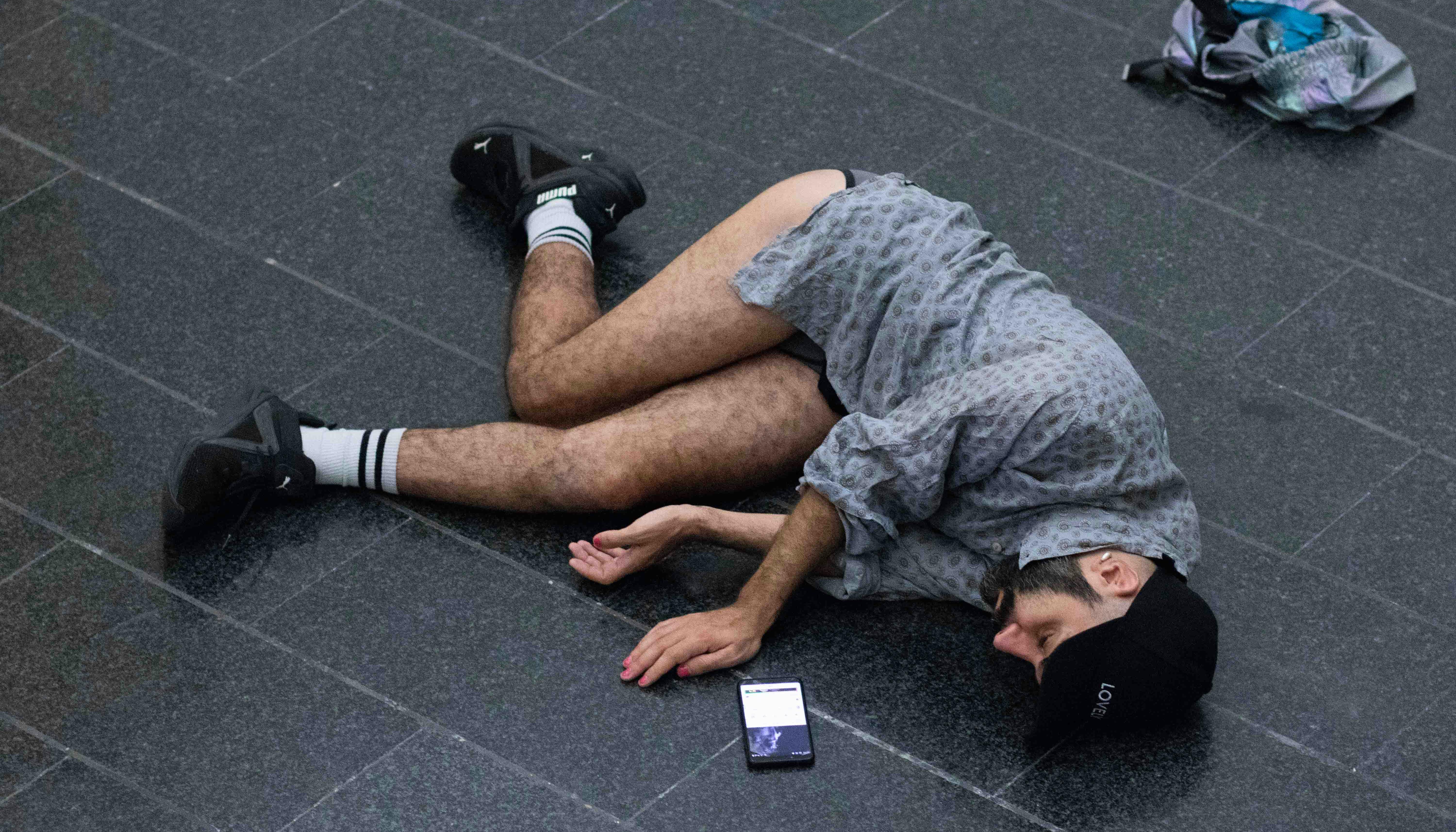 Daniele Ninarello is lying on the ground, on his side. He is wearing a shirt but not his pants, which are thrown on the floor next to him.