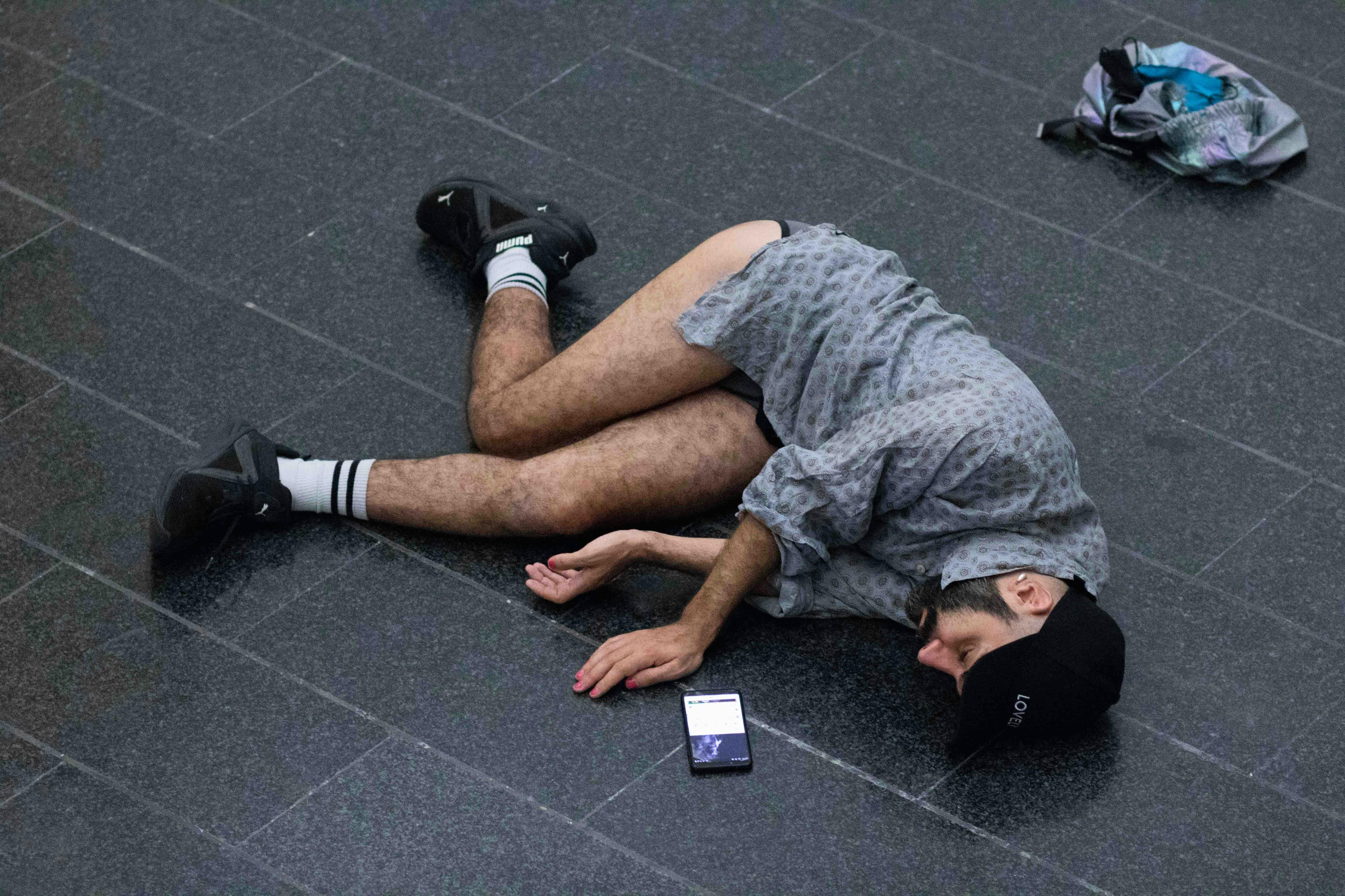 Daniele Ninarello is lying on the ground, on his side. He is wearing a shirt but not his pants, which are thrown on the floor next to him.