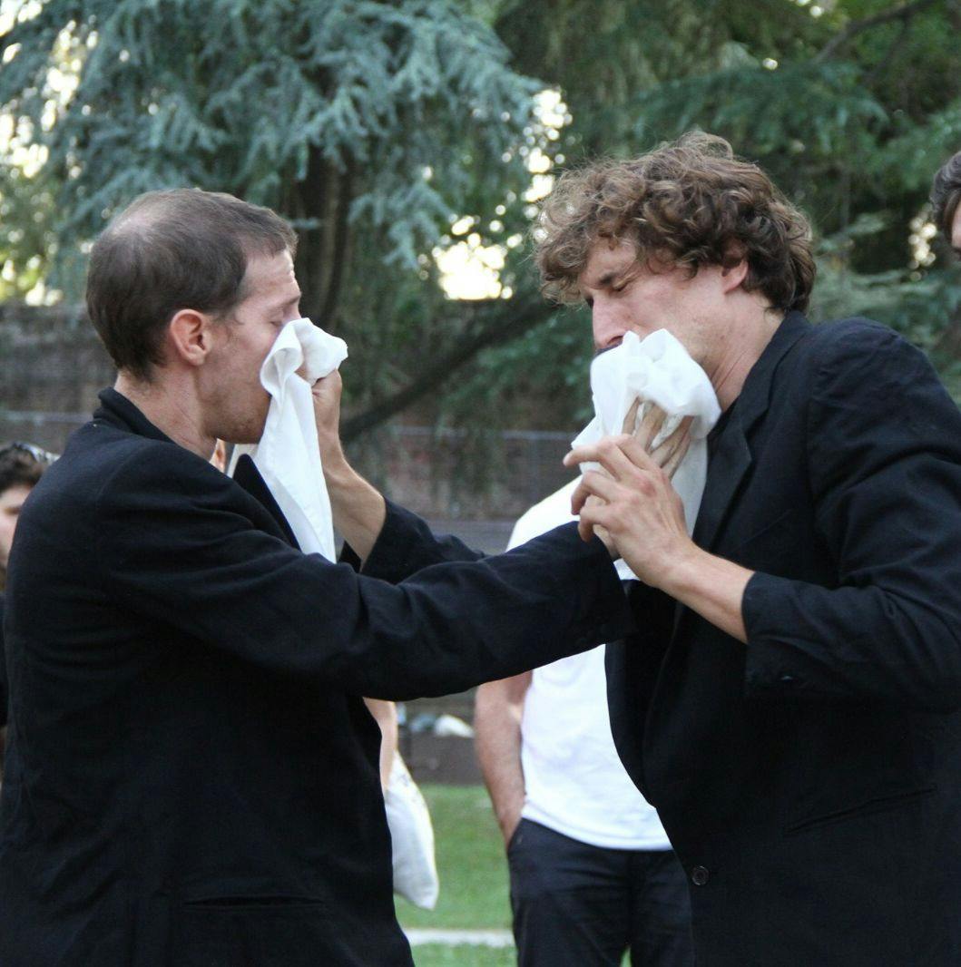 The two dancers cover each other's faces with white handkerchiefs