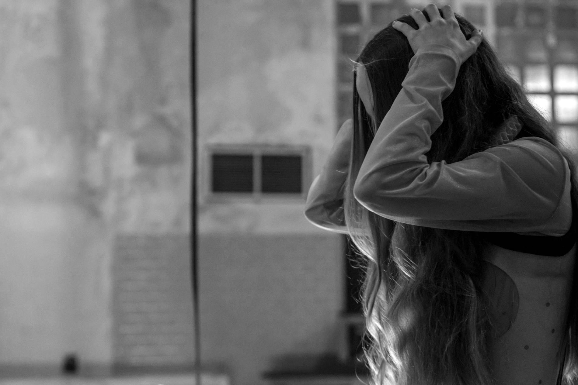 Girl with long hair holding her head with her hands