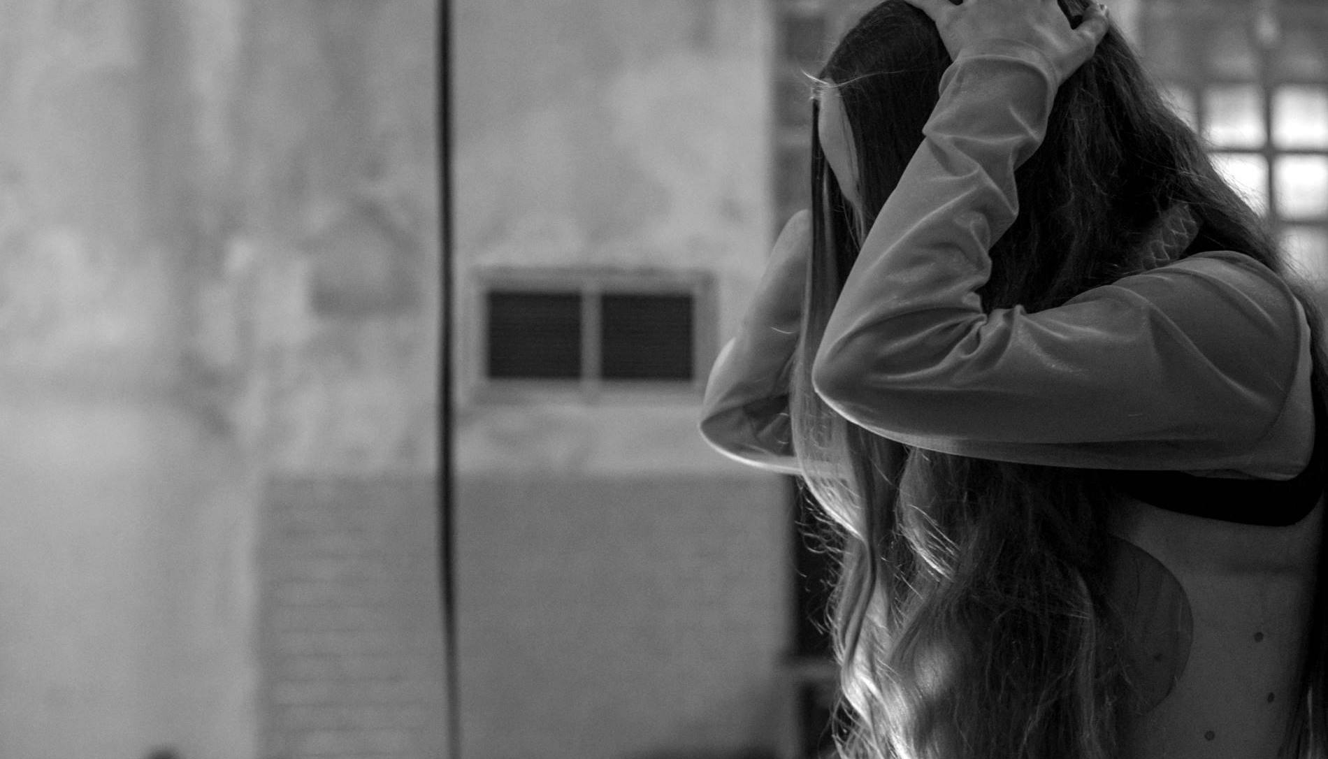 Girl with long hair holding her head with her hands