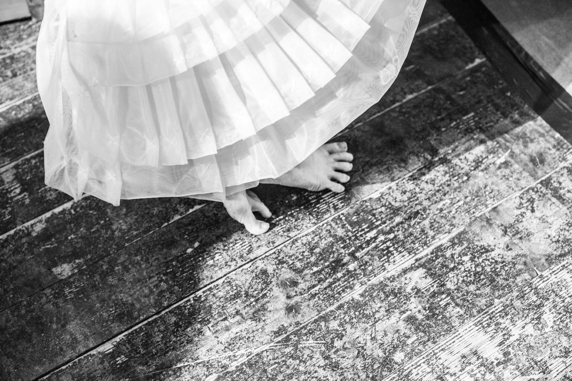 Black and white photo of a skirt and bare feet