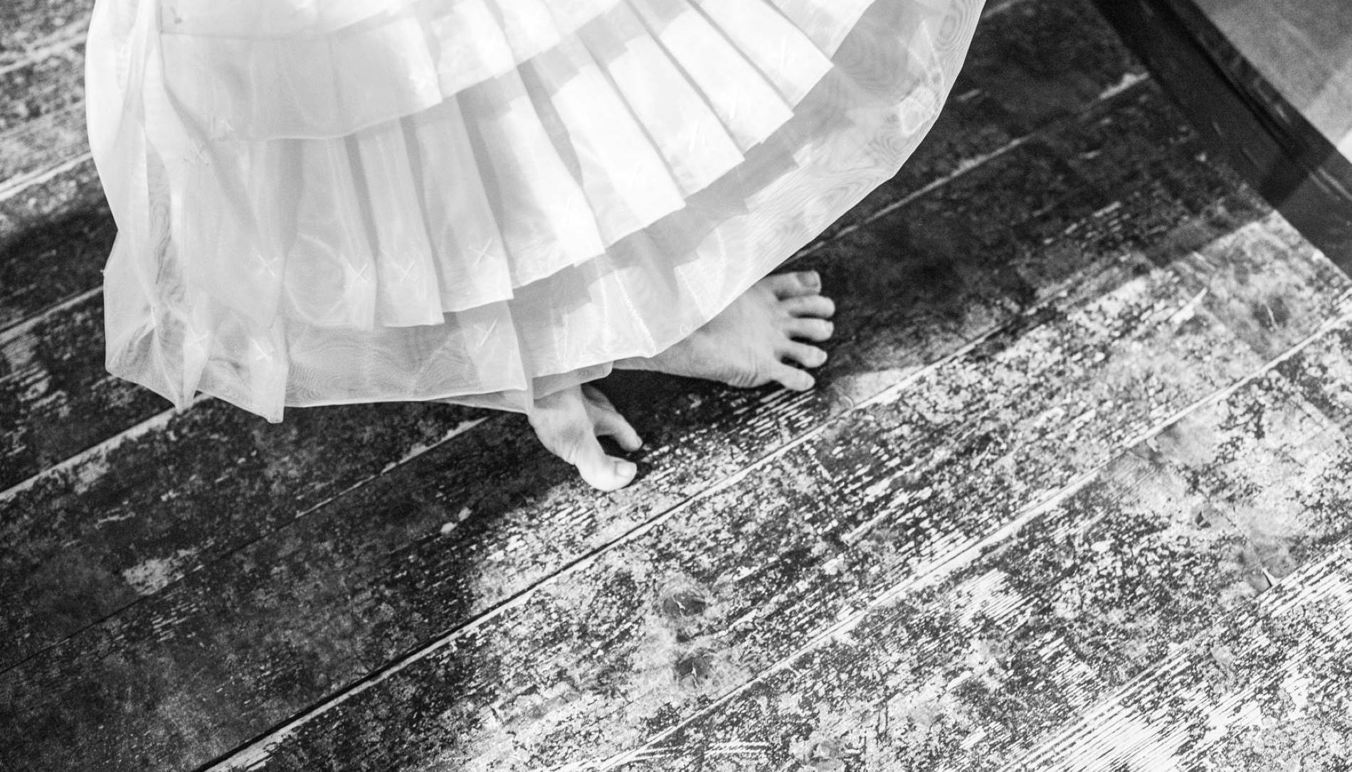 Black and white photo of a skirt and bare feet