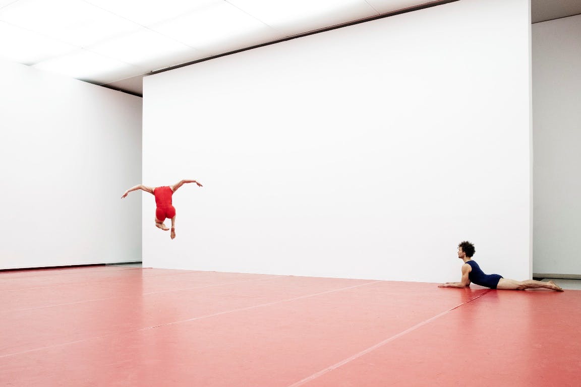 Two dancers dance in an empty hall with red dance carpet