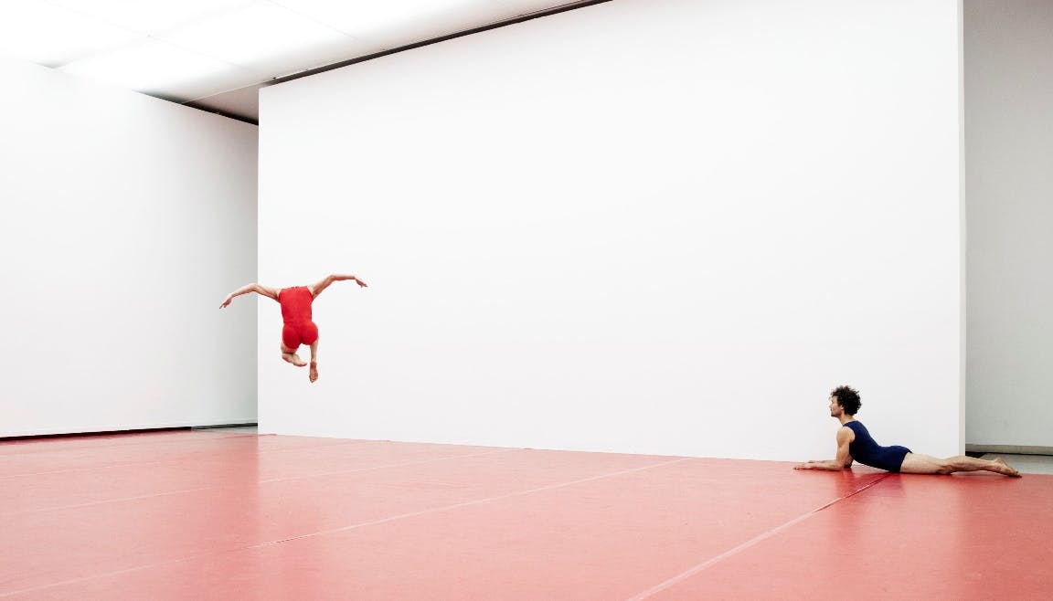 Two dancers dance in an empty hall with red dance carpet