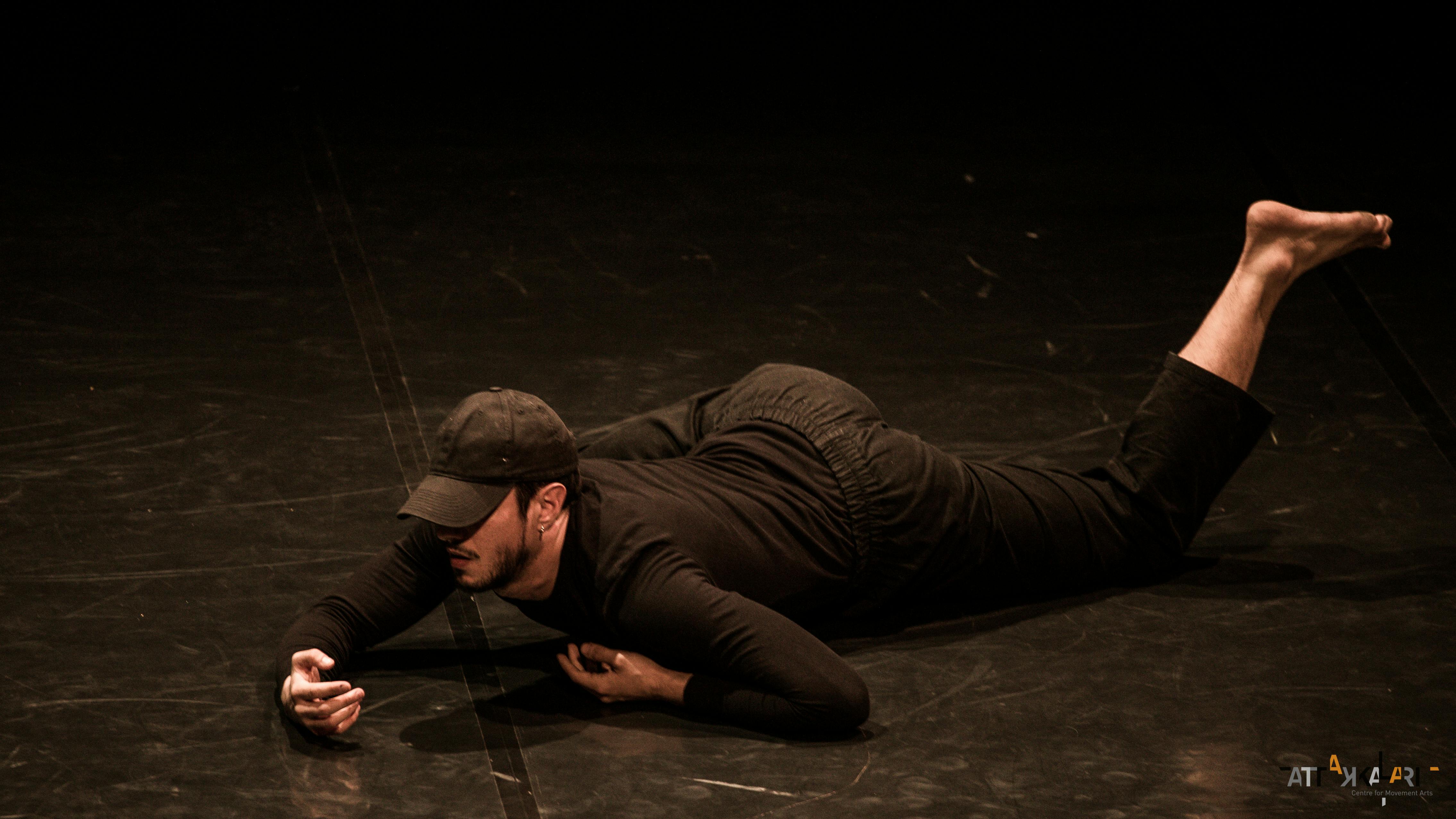 Davide Valrosso on stage lying down and dressed in black