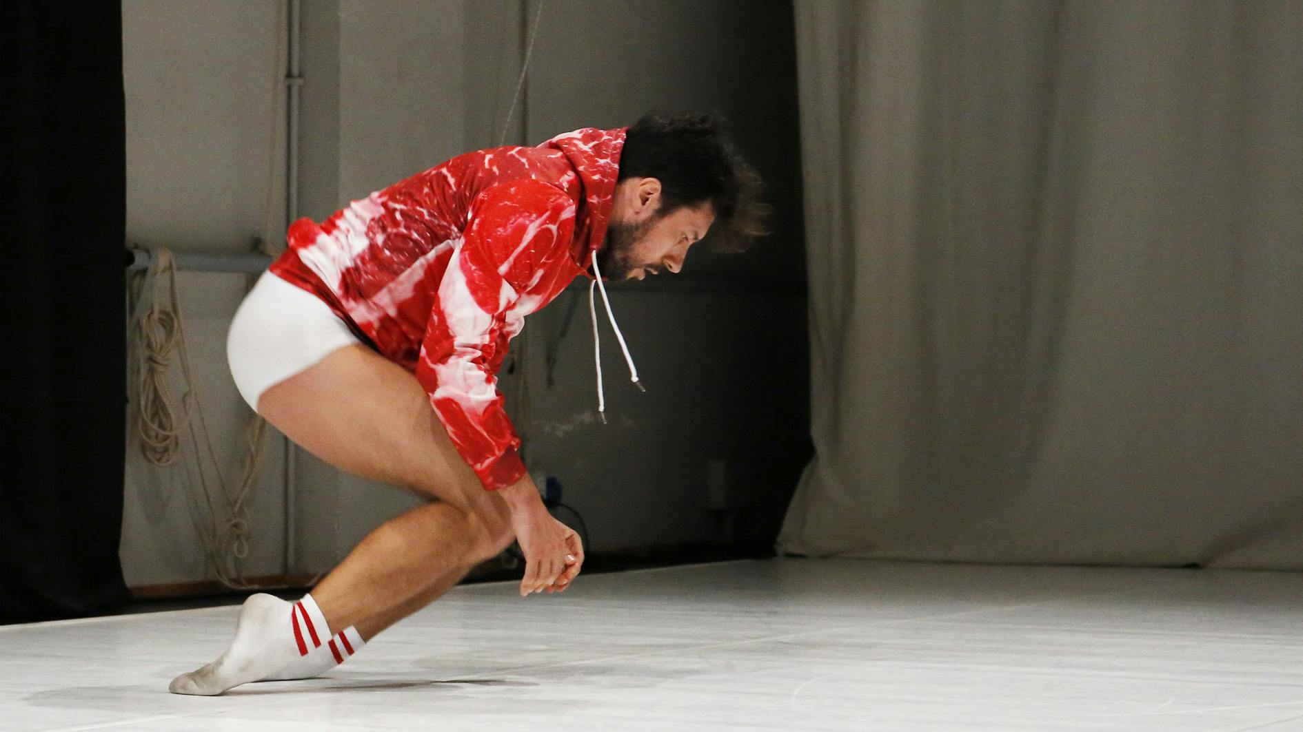 Carlo Massari wears a red and white sweatshirt and balances on the back of his feet 