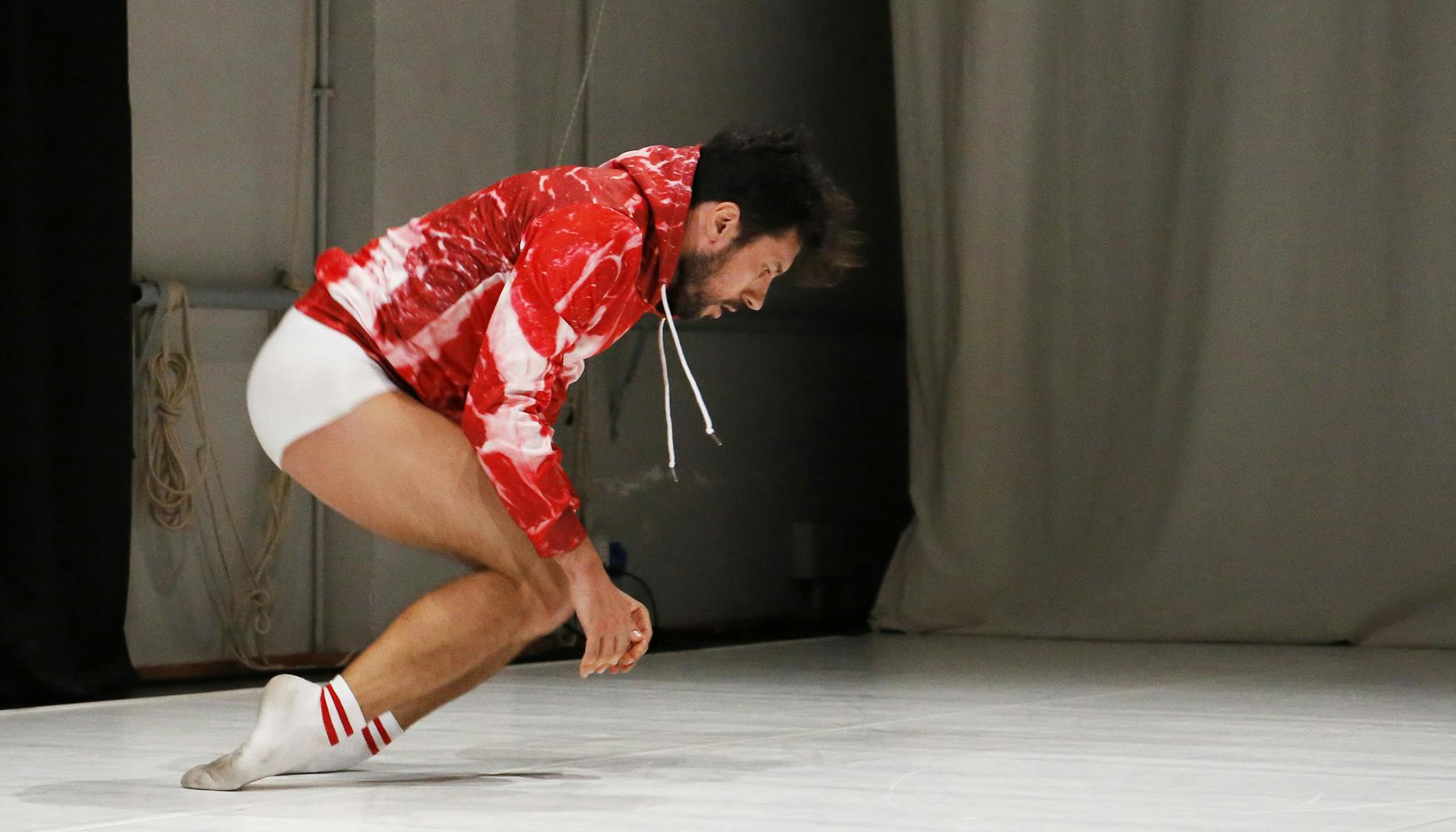 Carlo Massari wears a red and white sweatshirt and balances on the back of his feet 