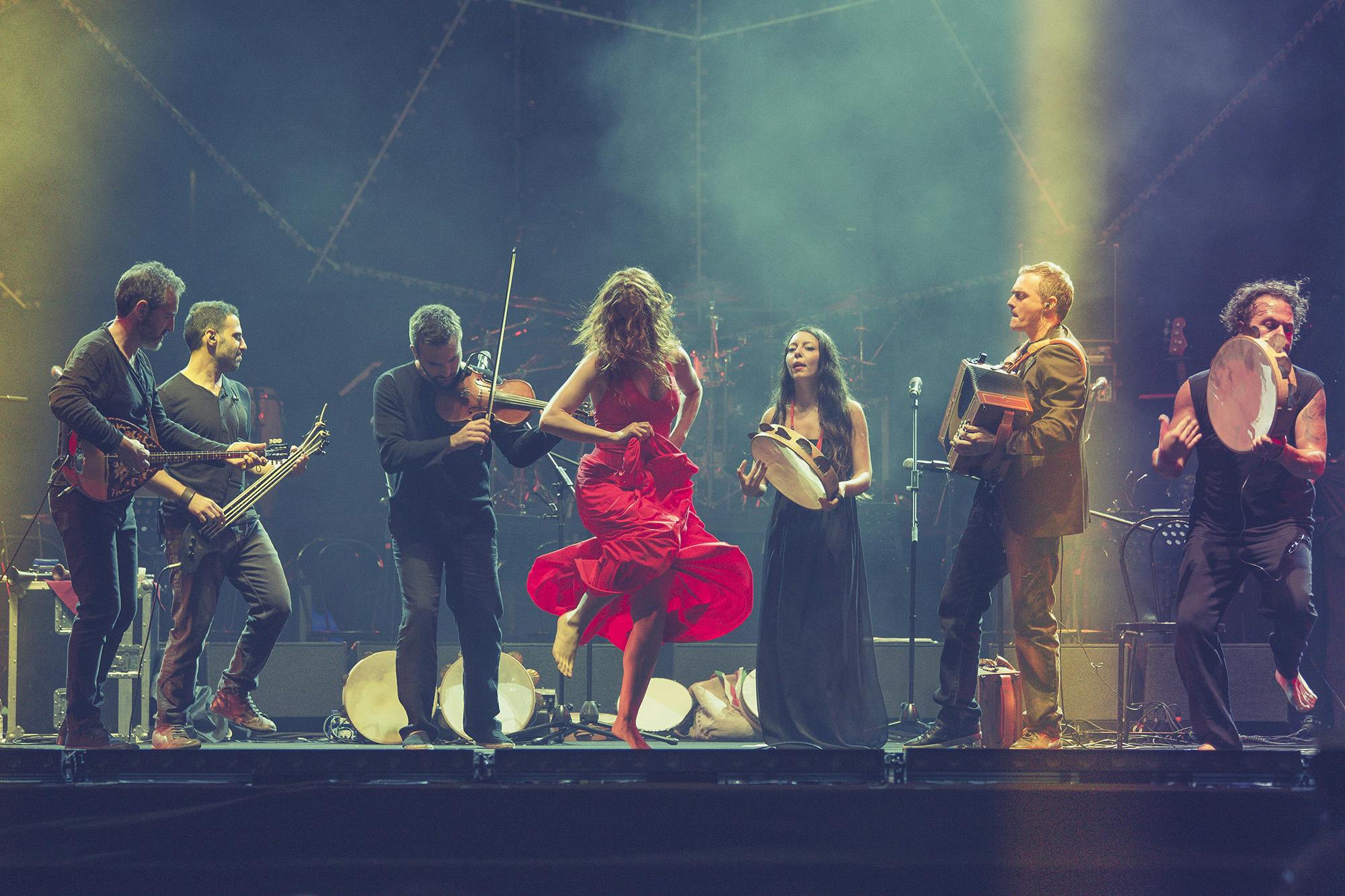 CGS musicians dressed in black form a semicircle around a pizzica dancer 