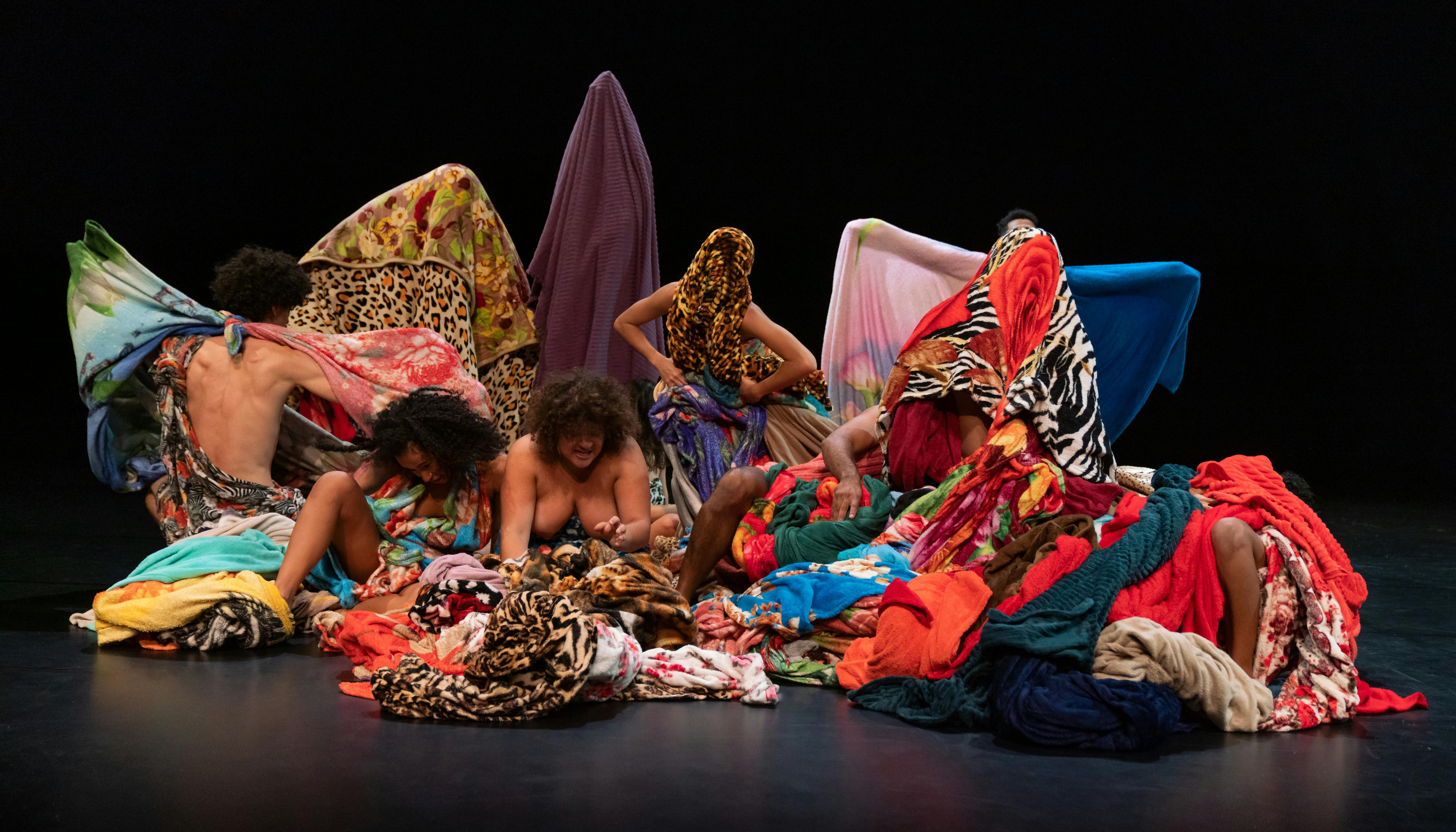 The performers of Lia Rodrigues' company wrap themselves and hide in colourful fabrics 