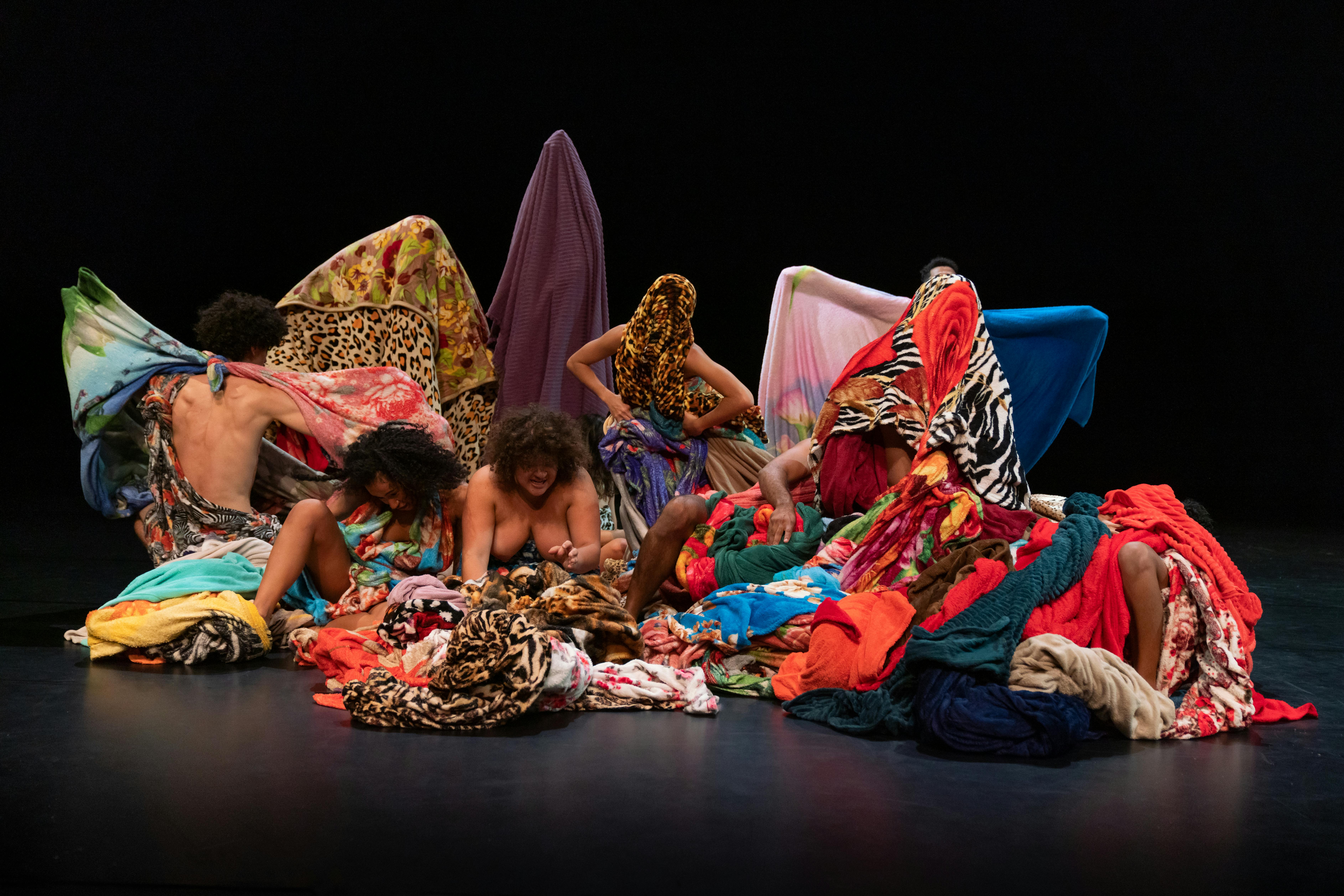Gli interpreti della compagnia di Lia Rodrigues si avvolgono e nascondono con tessuti colorati 