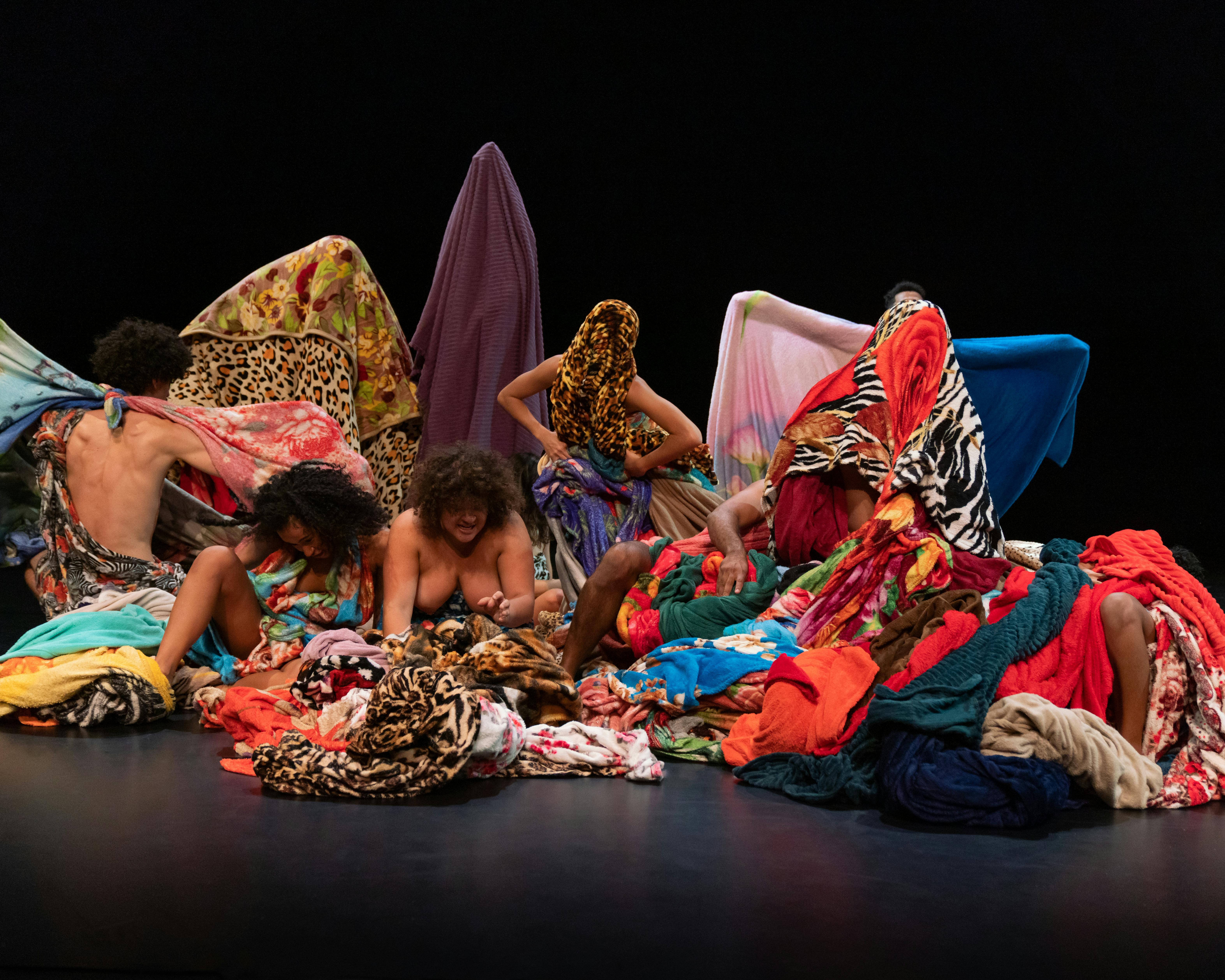 The performers of Lia Rodrigues' company wrap themselves and hide in colourful fabrics 