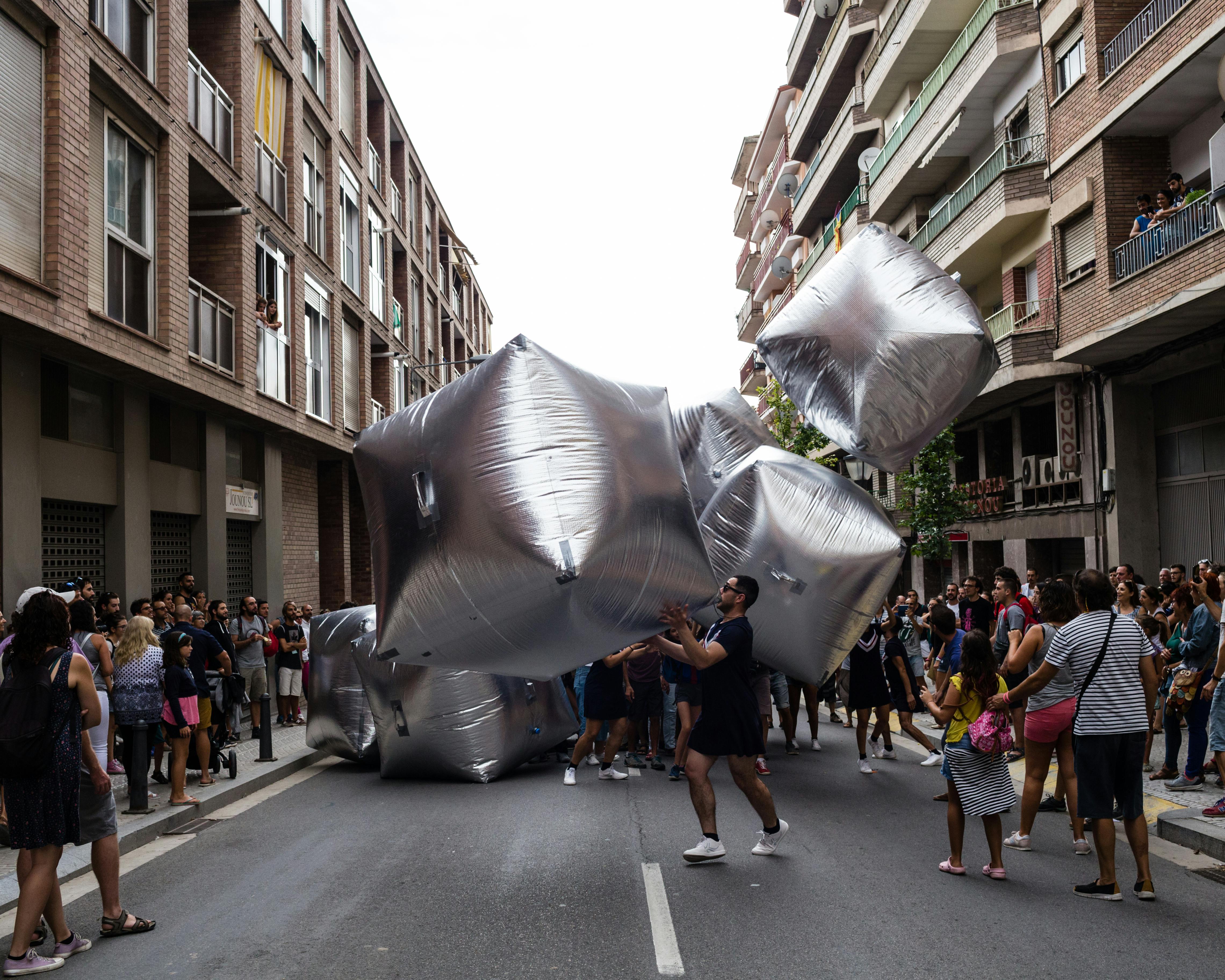 I danzatori si esibiscono con i cubi d'argento gonfiabili per le strade della città
