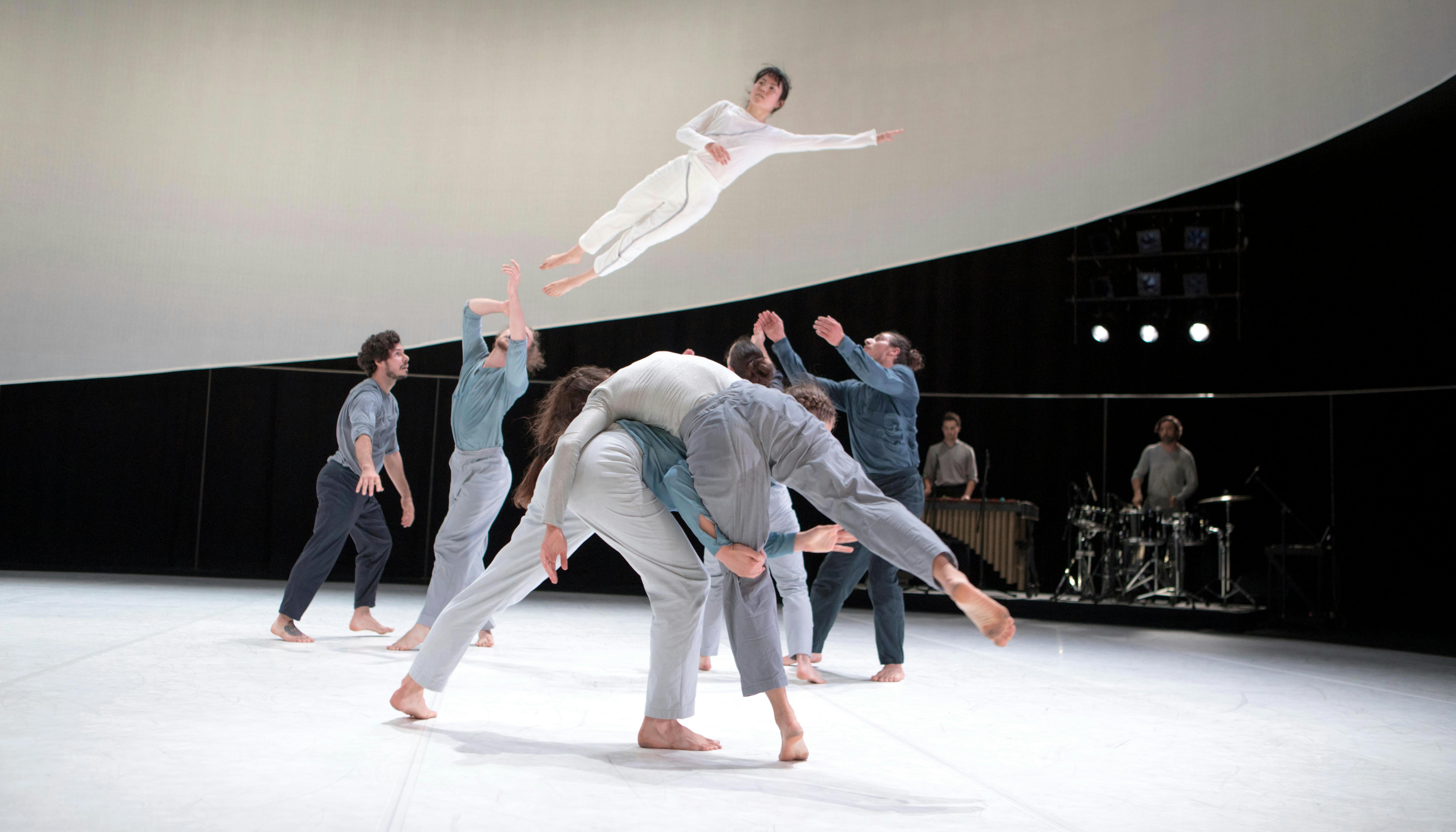 The artists perform wearing light-coloured garments 