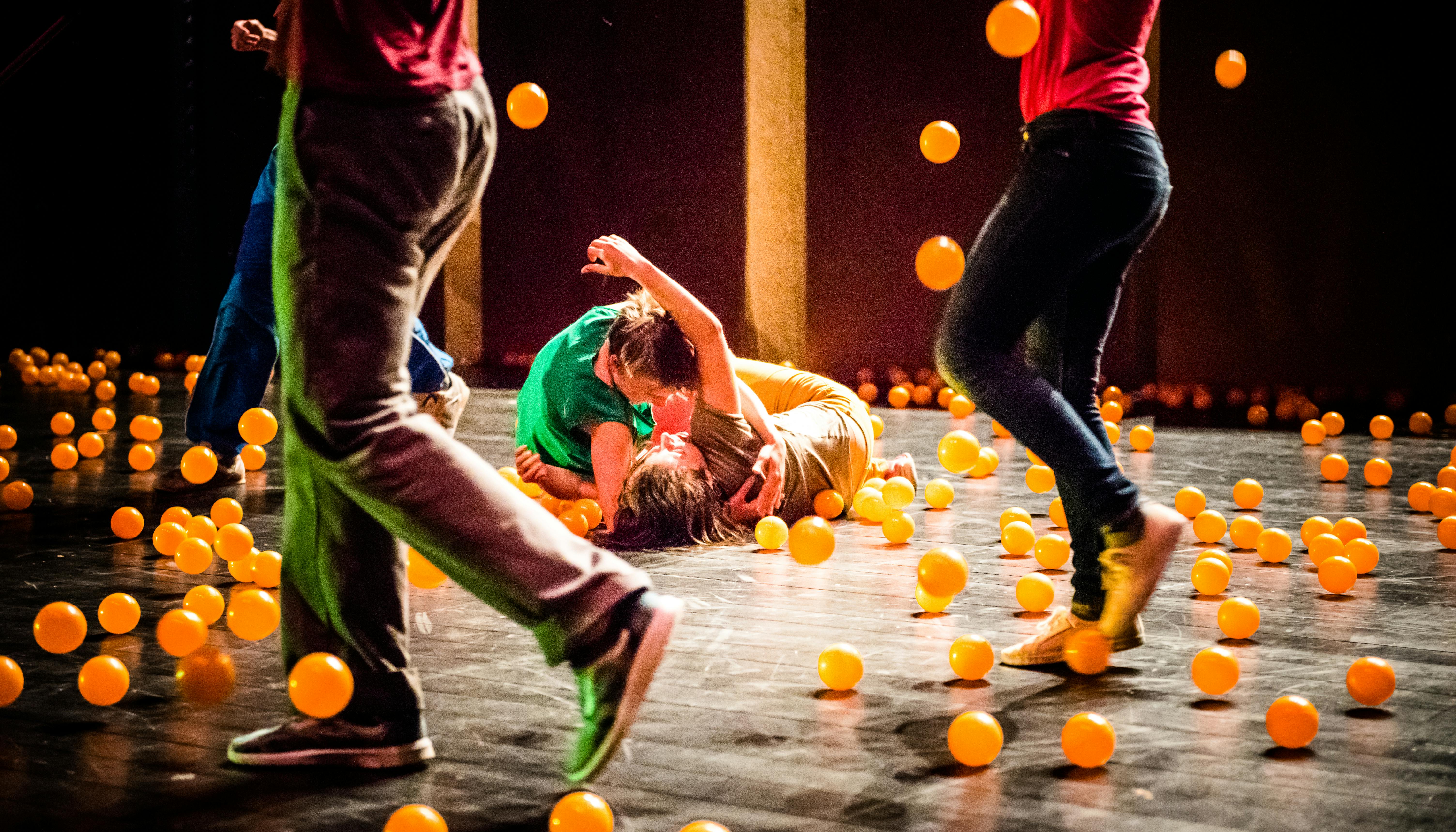 The artists perform on stage surrounded by orange balls