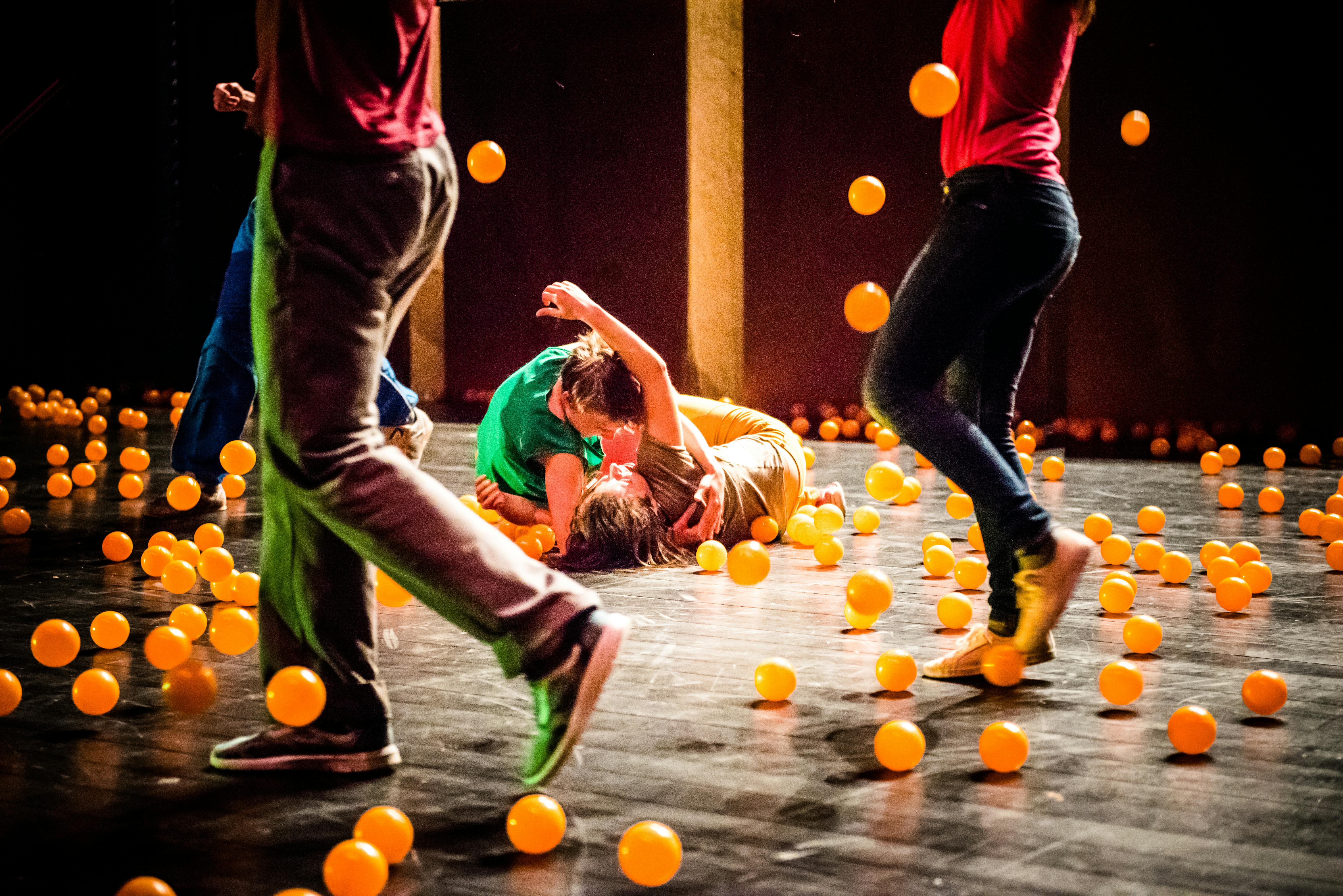 The artists perform on stage surrounded by orange balls