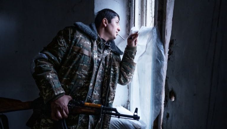 Fotografia di un soldato con fucile in mano che guarda fuori dalla finestra