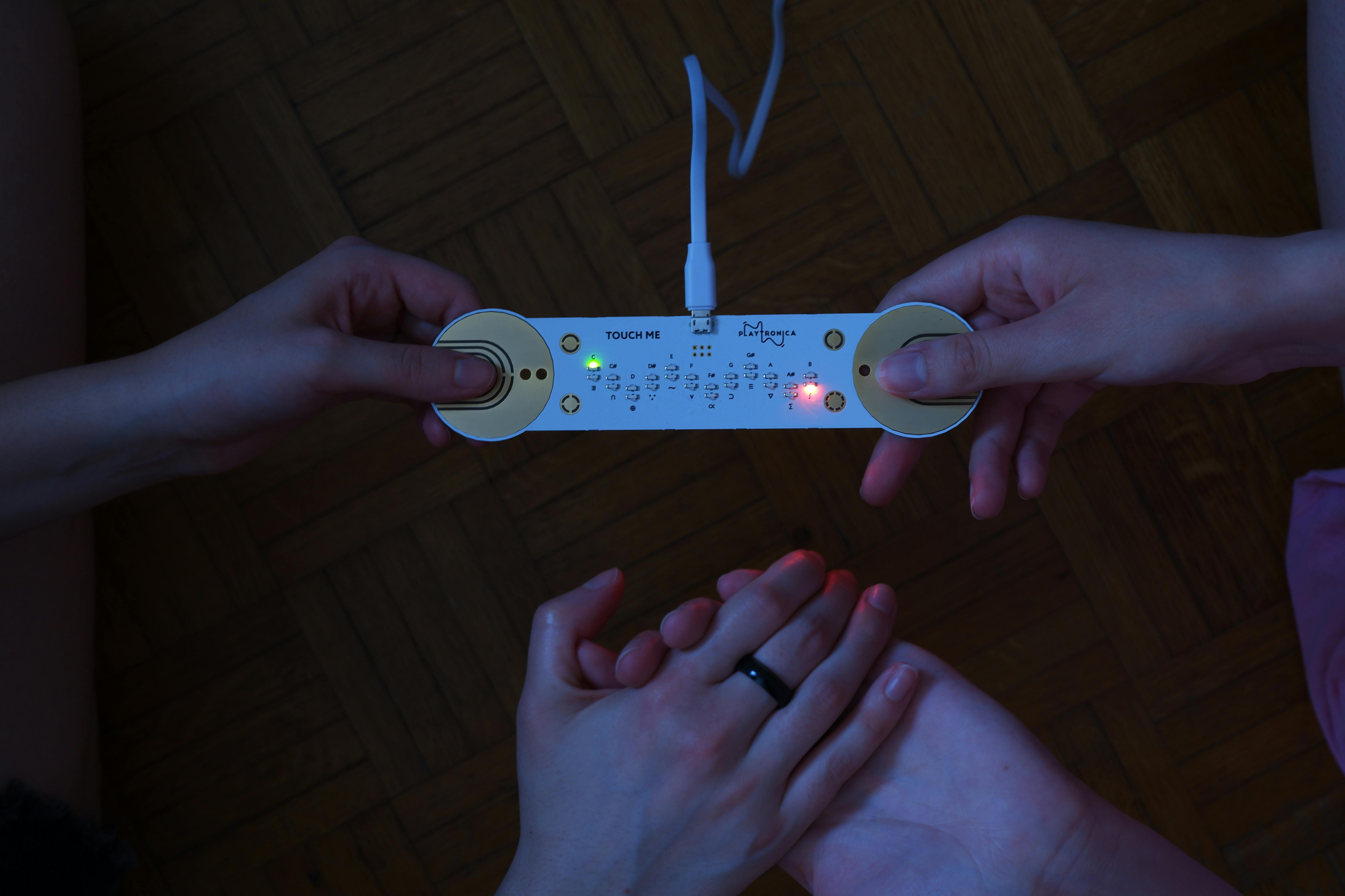 Picture of the TouchMe technology device being used by two people holding hands