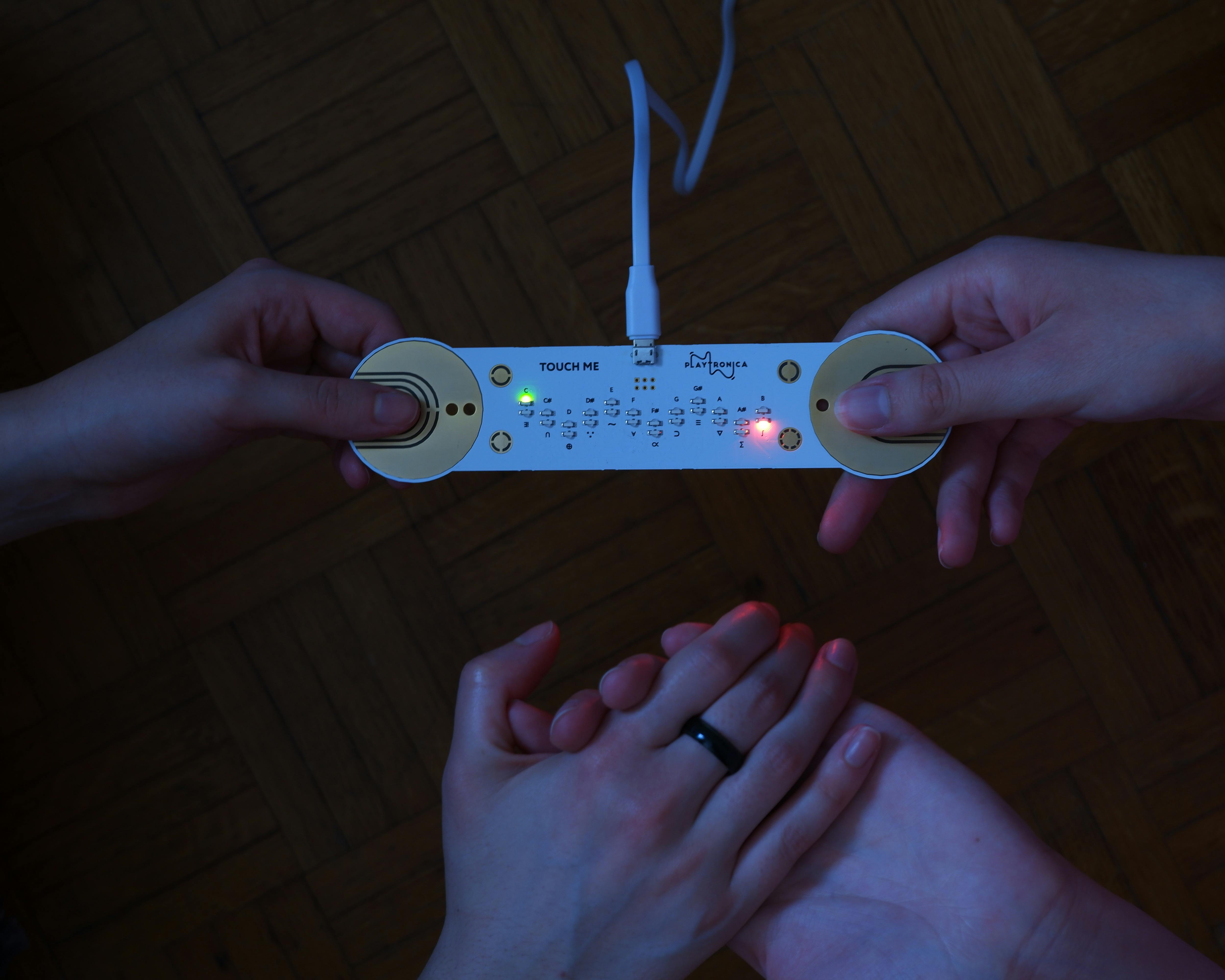 Picture of the TouchMe technology device being used by two people holding hands