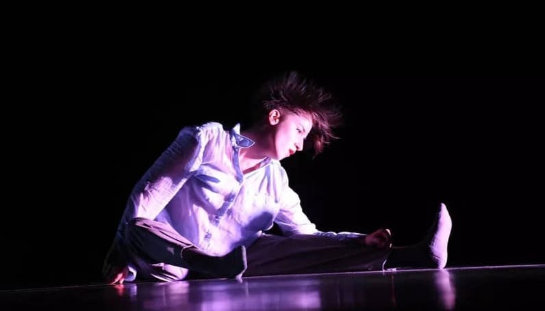 Immagine della performer Dora Schembri seduta su un palco