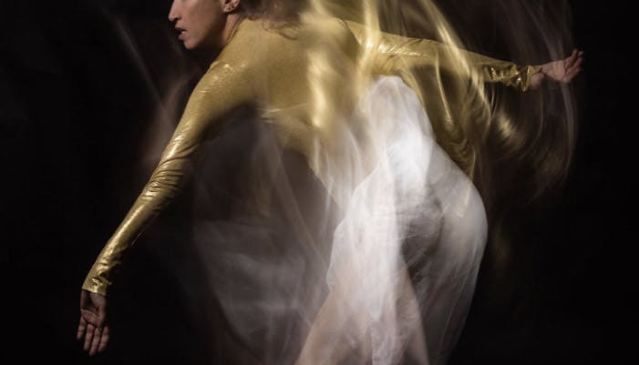 Adi Salant wearing a gold long-sleeved leotard in a photo with movement effect