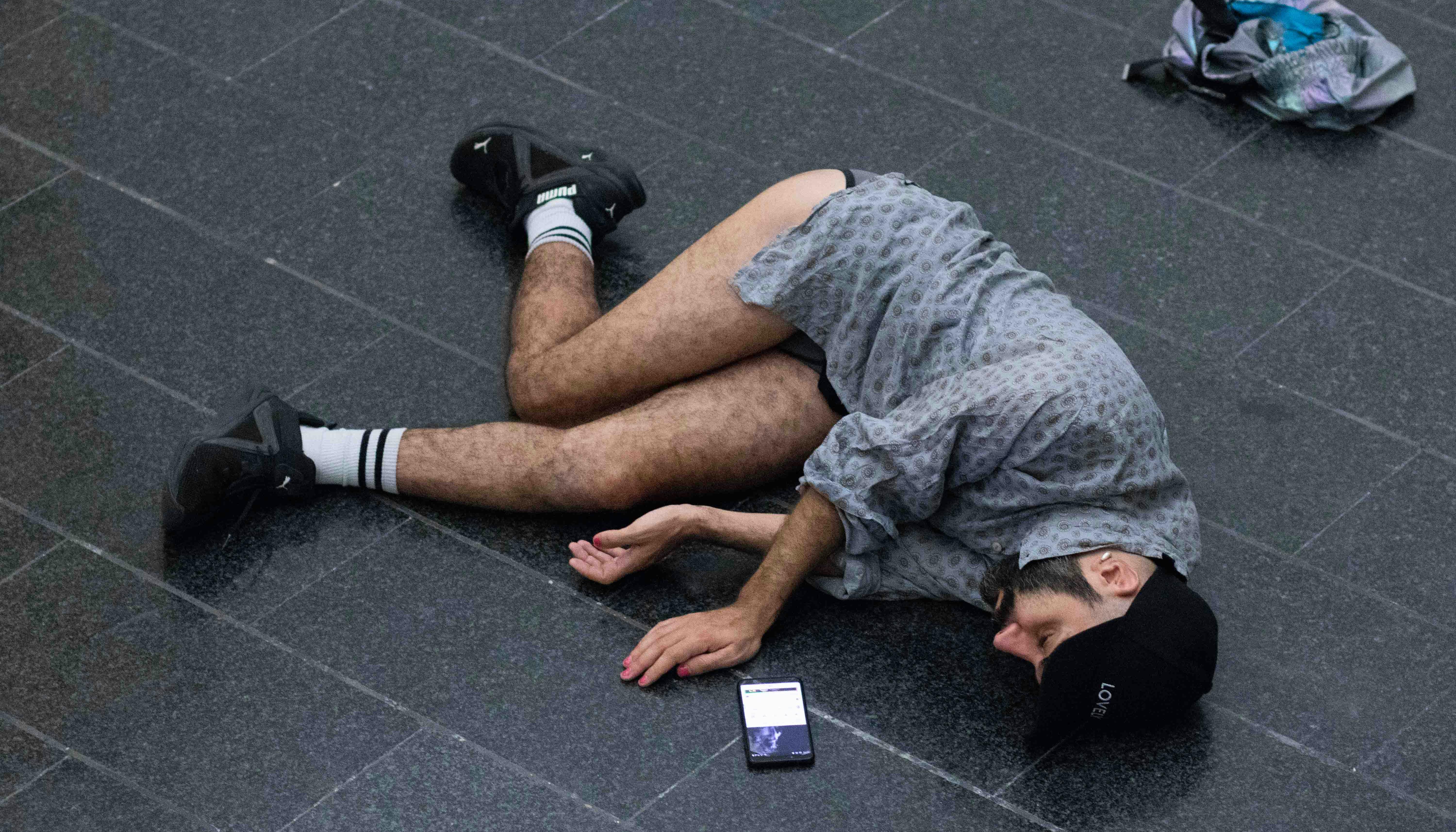 Daniele Ninarello sdraiato in posizione fetale con uno smartphone a fianco