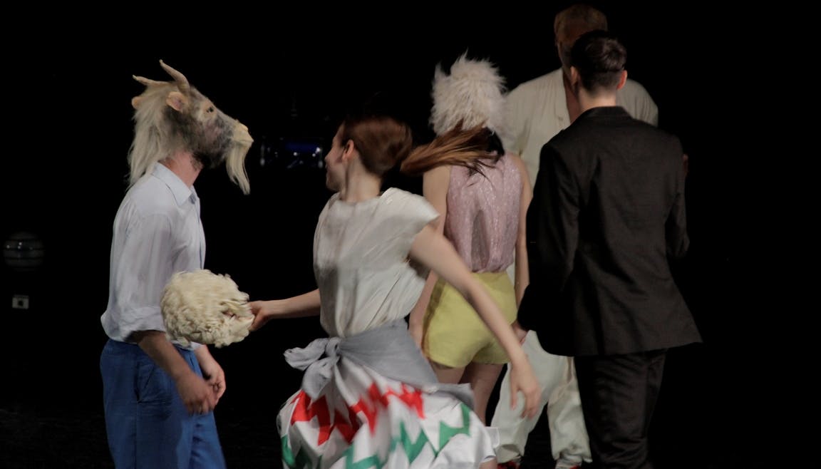 Five dancers on stage with ordinary clothes and sheep masks on their faces 
