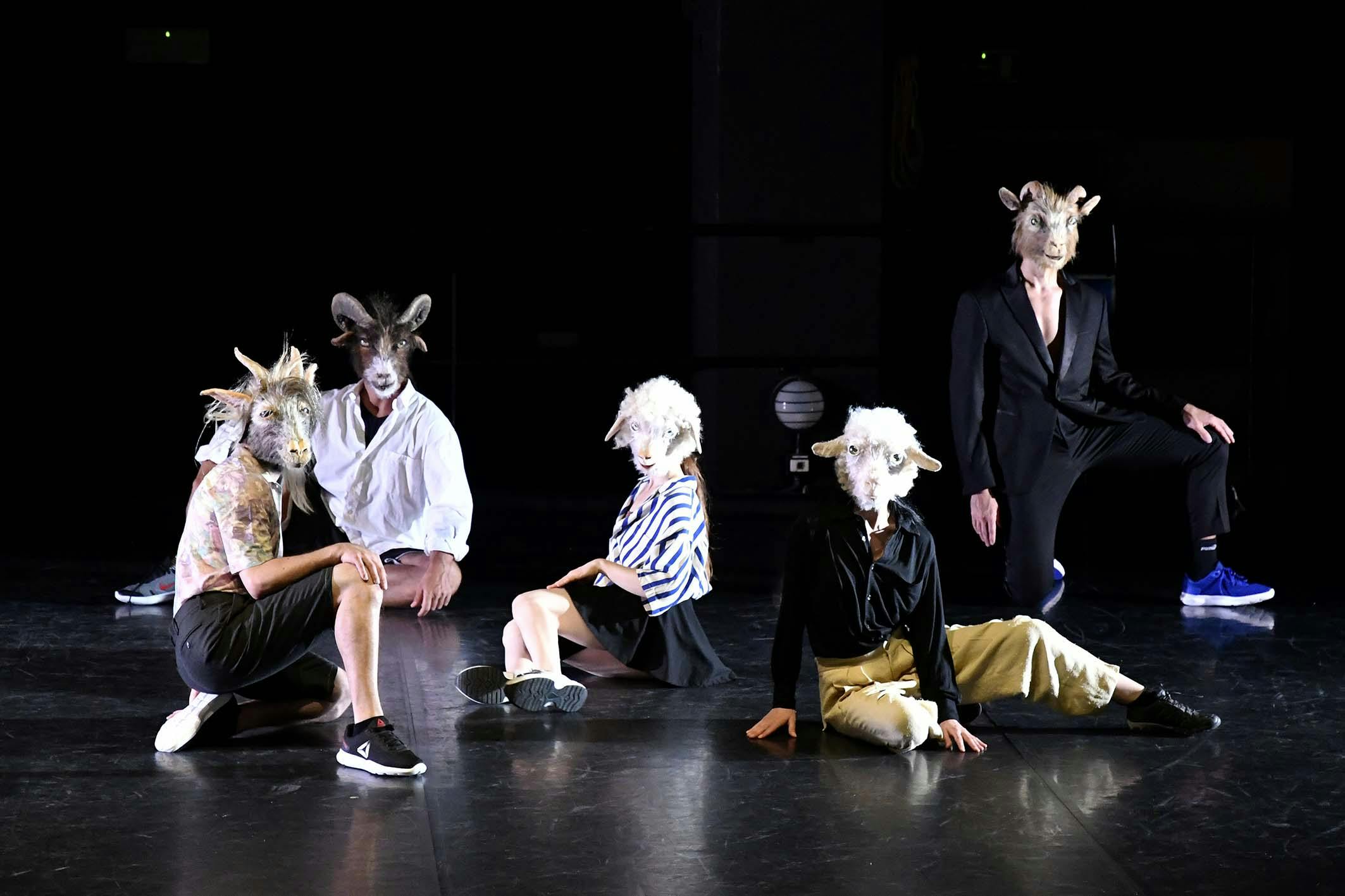 Cinque interpreti in diverse pose sul palco con vestiti ordinari e maschere di animali sul volto 