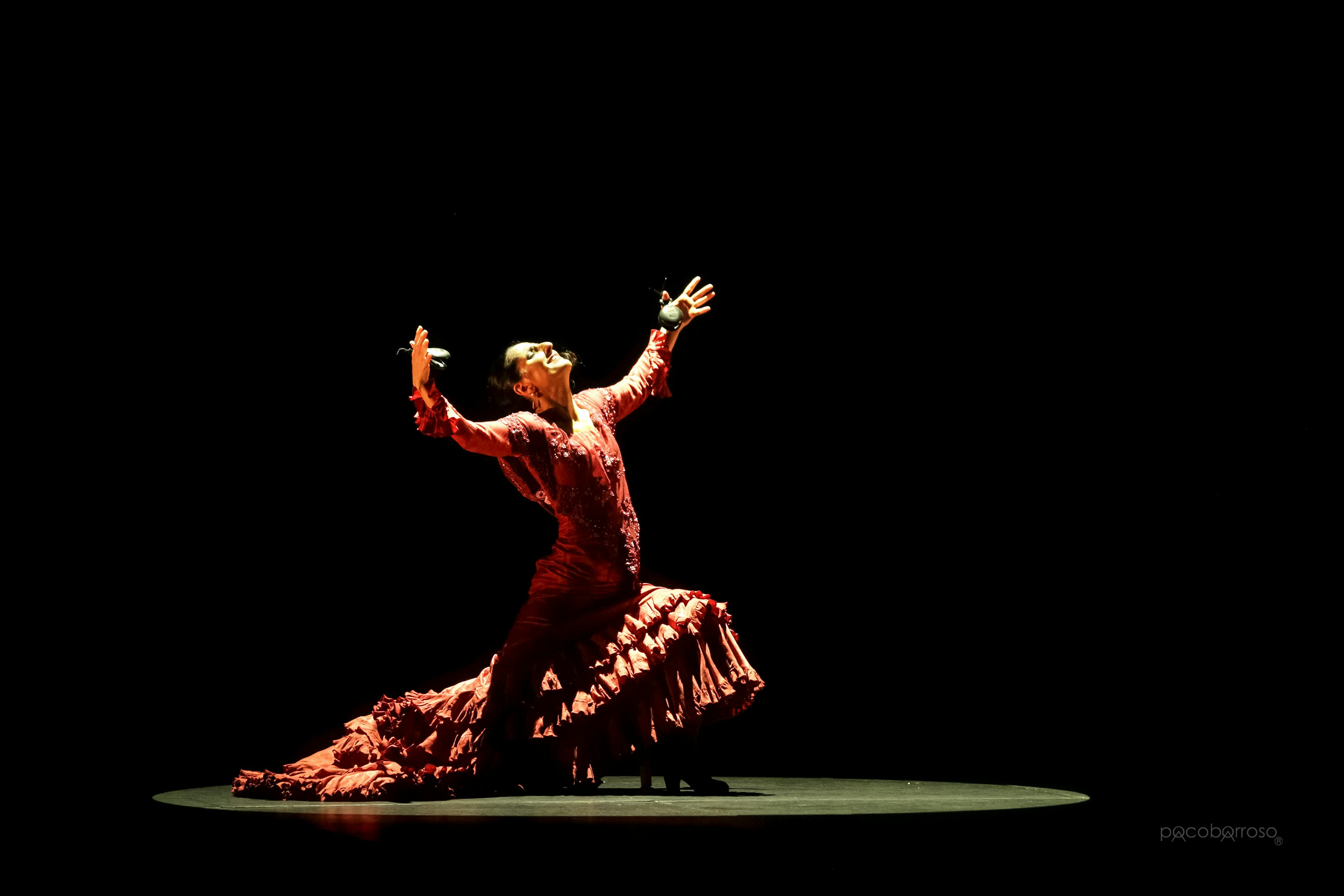 Mercedes Ruiz sul palco con le nacchere in mano in una posizione di apertura verso l'alto