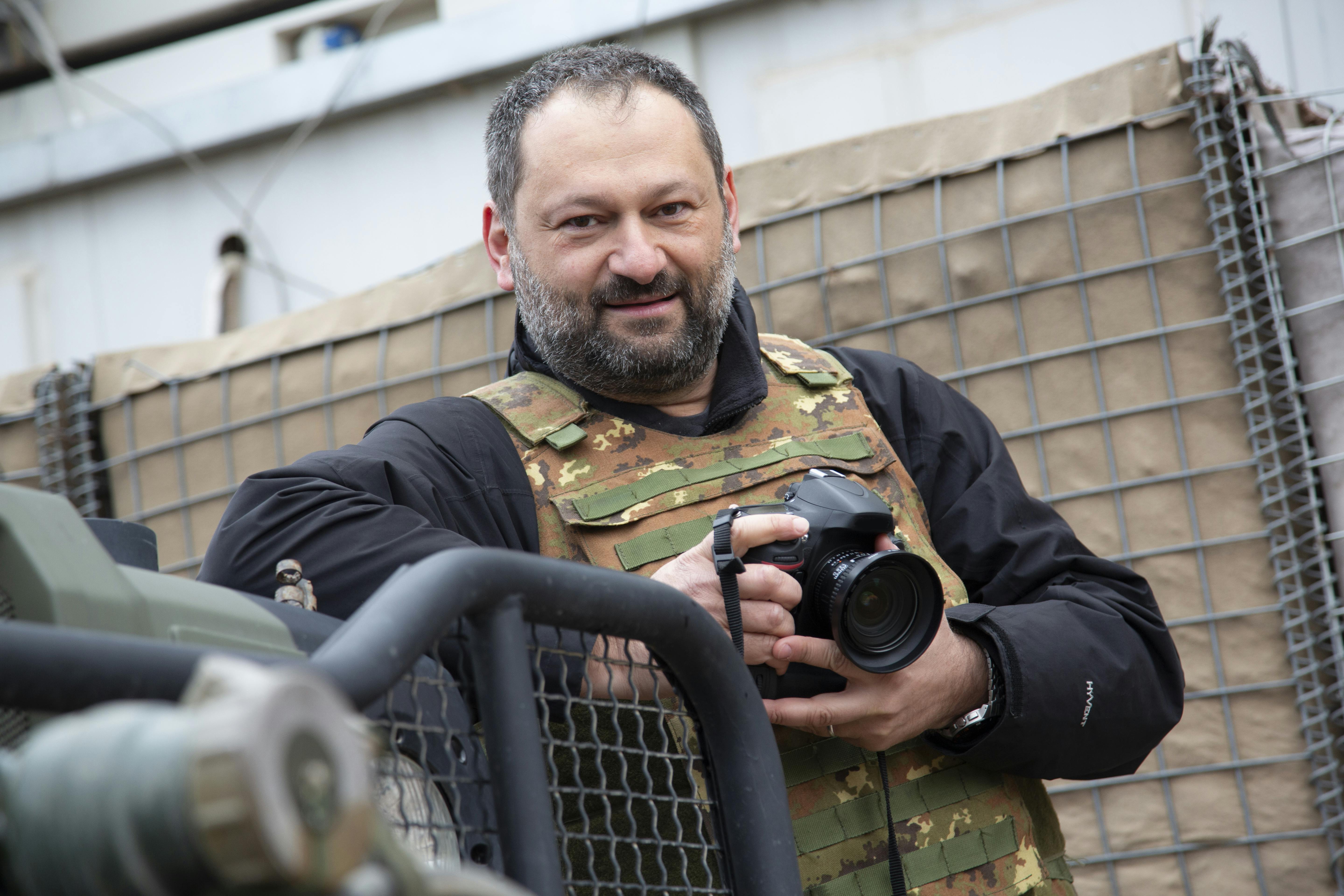 Roberto Travan, fotogiornalista di guerra con giubotto antiproiettile e macchina fotografica in mano