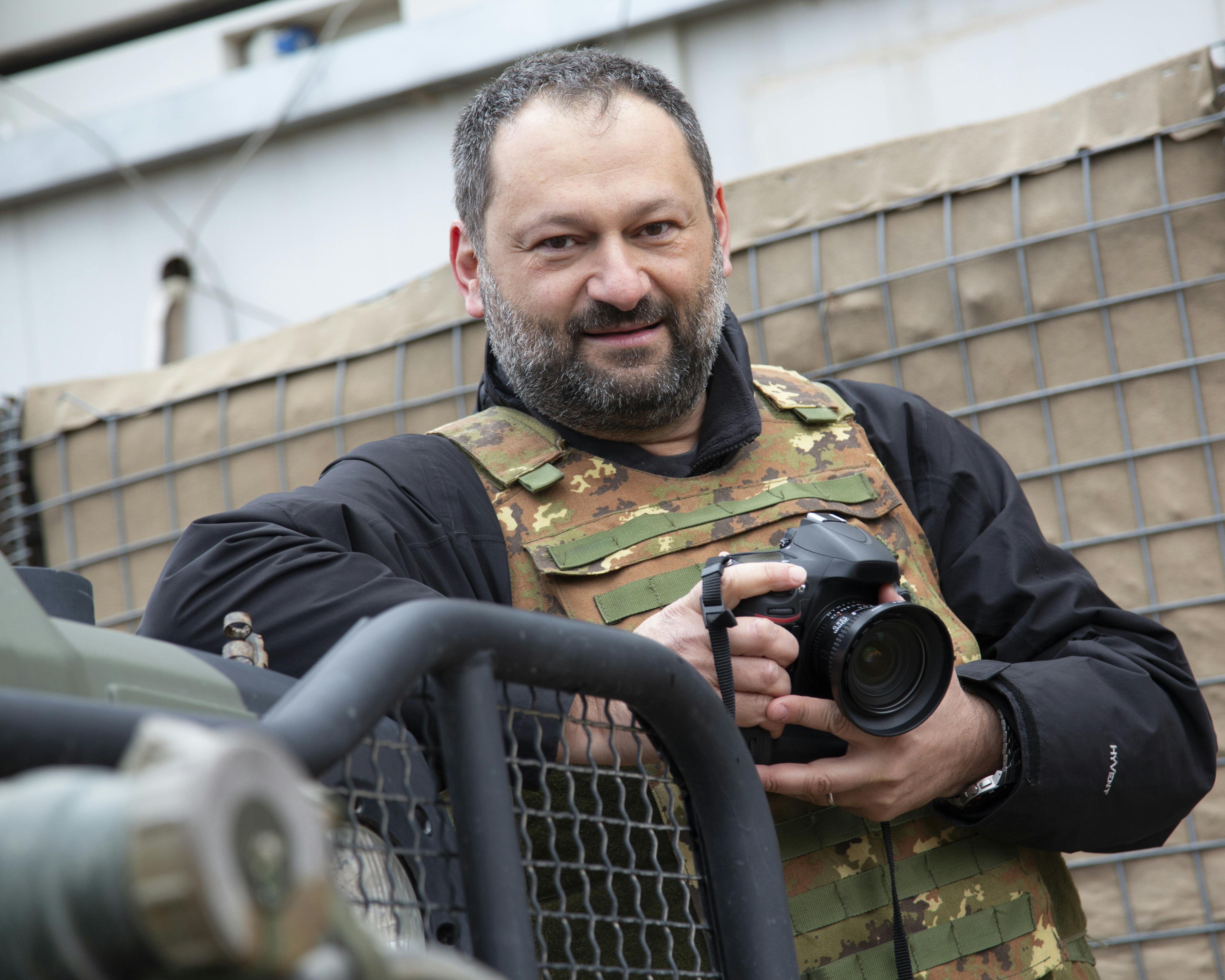 Roberto Travan, fotogiornalista di guerra con giubotto antiproiettile e macchina fotografica in mano