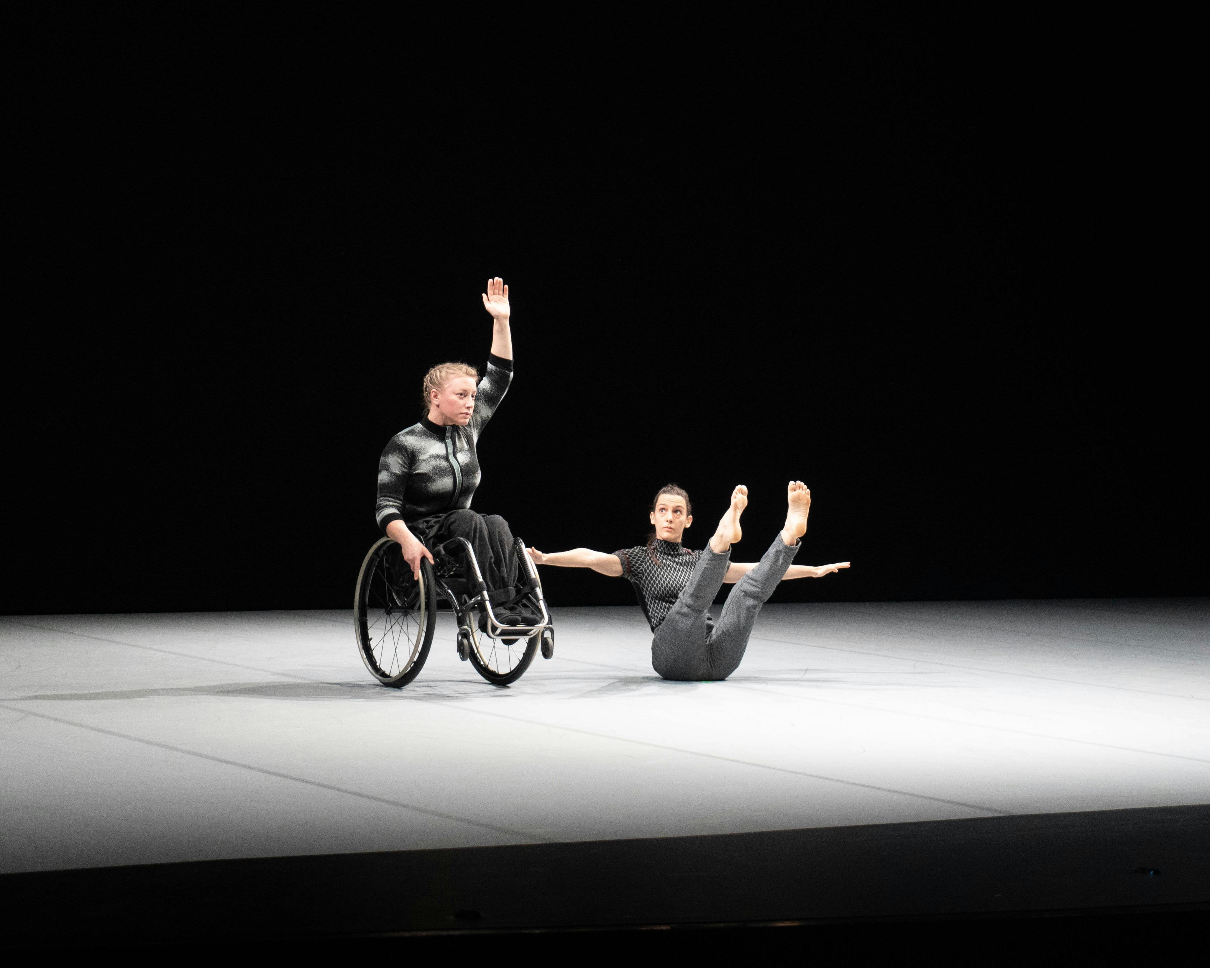 Due danzatrici, la prima da sinistra in equilibrio sulle ruote della carrozzina la seconda al suo fianco in equilibrio sul bacino