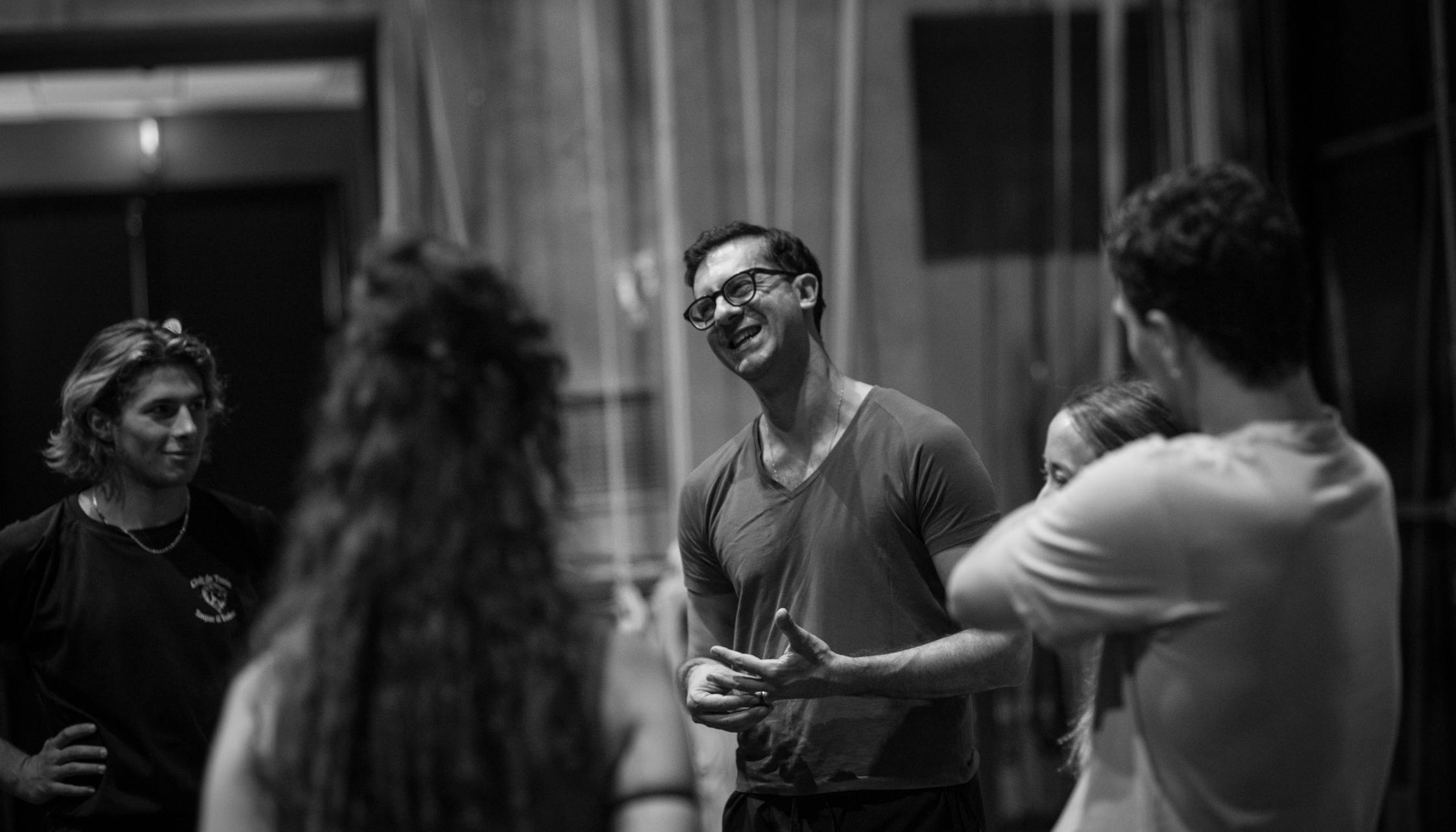 Alessio Maria Romano in a black and white photo conversing with a group of interpreters