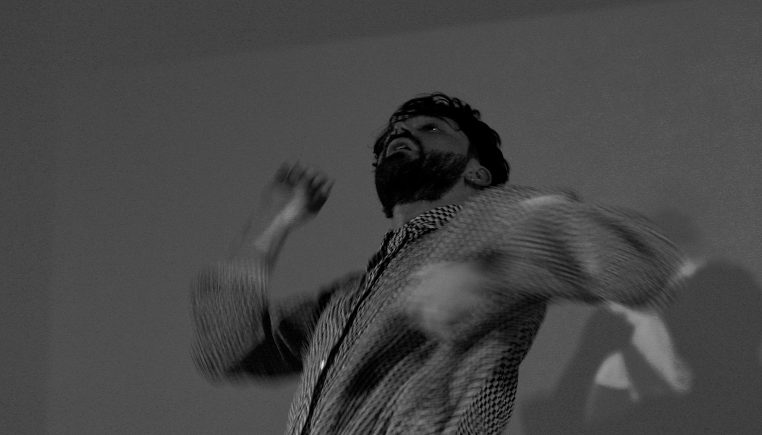 Simone Donati in una foto in bianco e nero sfuocata muove le braccia