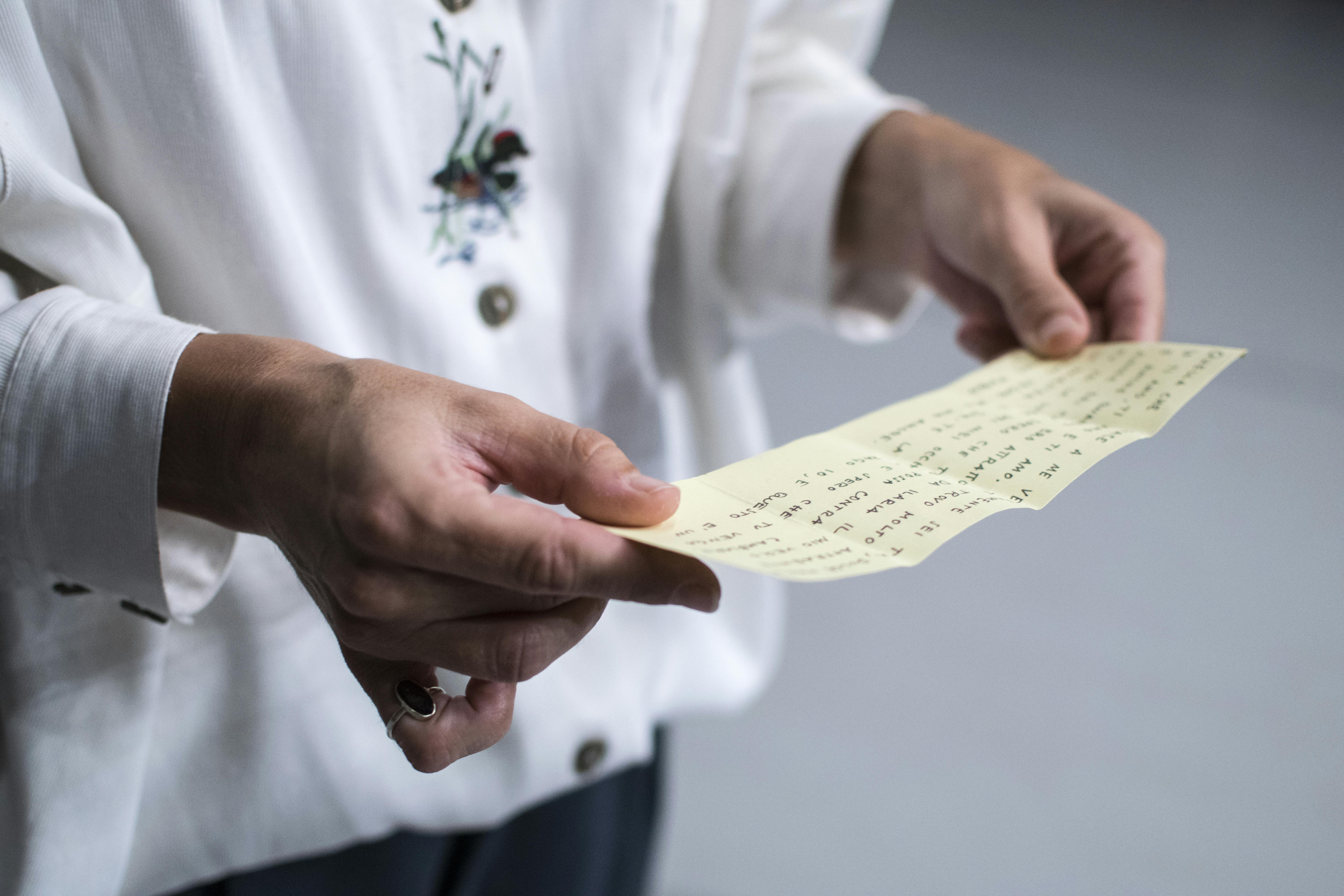 Primo piano di due mani che tengono un foglio scritto