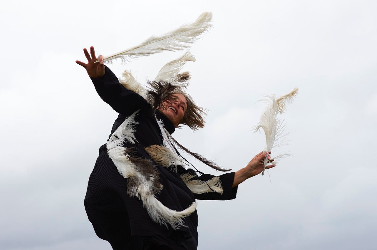 Artist Kirstie Simson in motion with feathers on her dress and in her hand