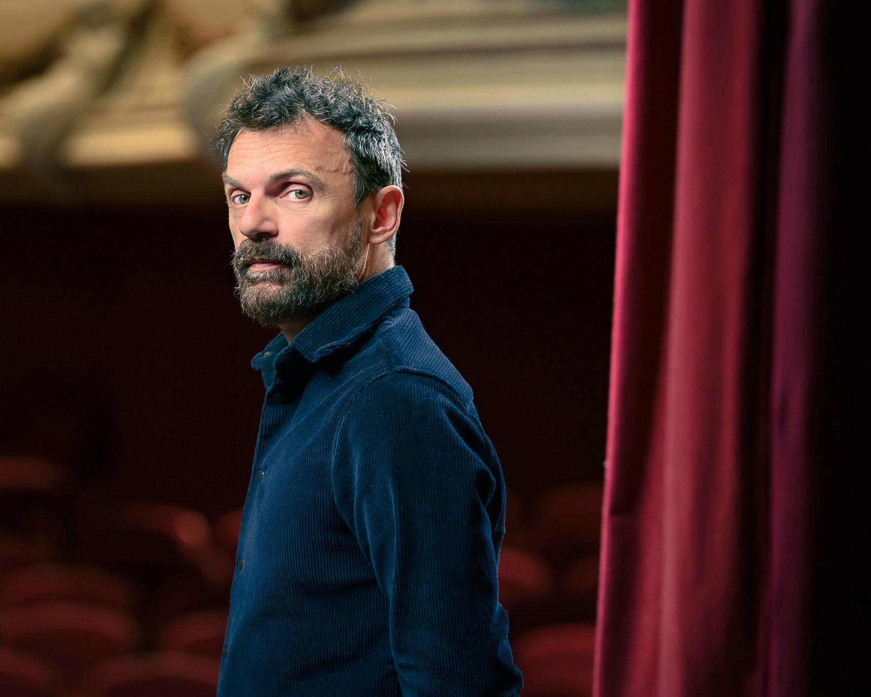 Portrait of Emilio Calcagno in a theater wearing a blue shirt
