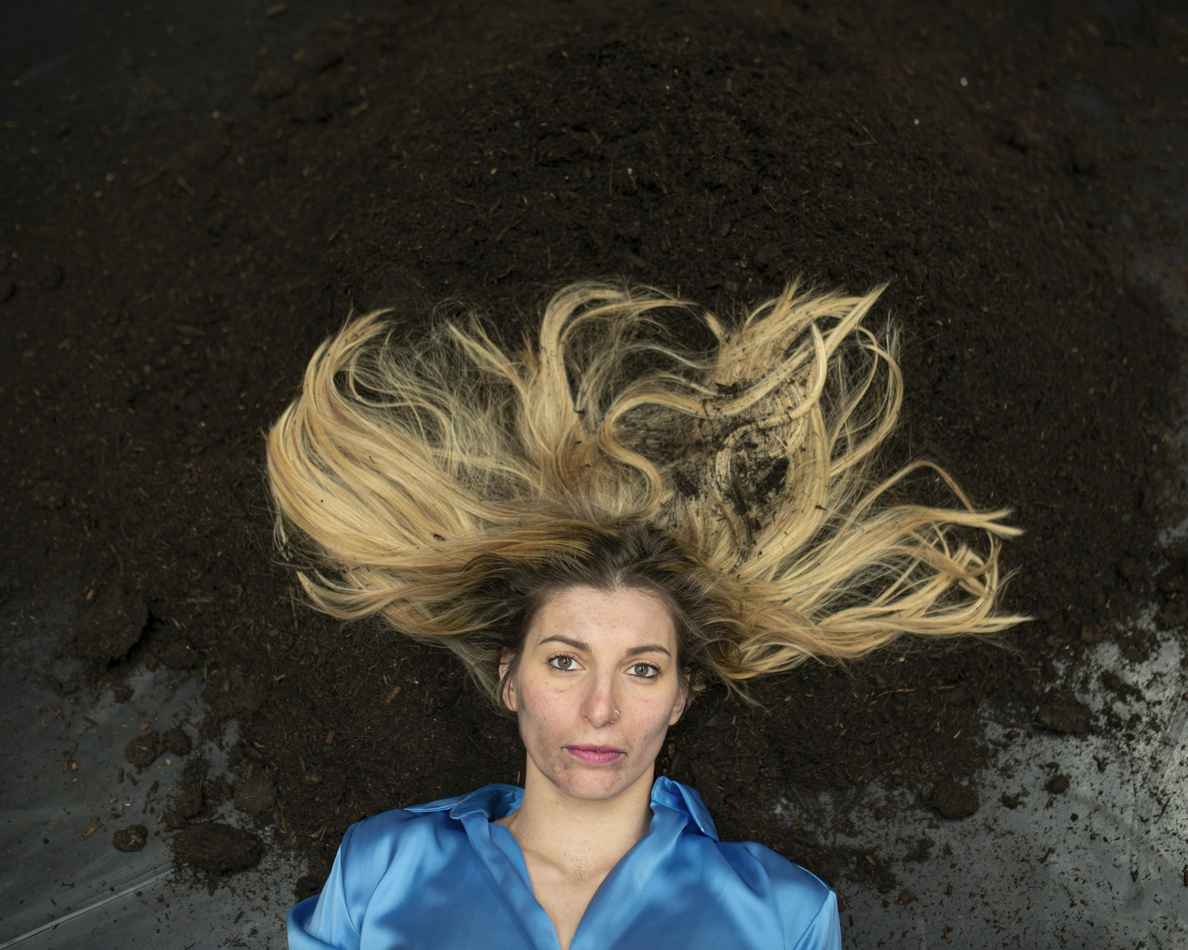 Performer lying on the earth spread out on a carpet dances