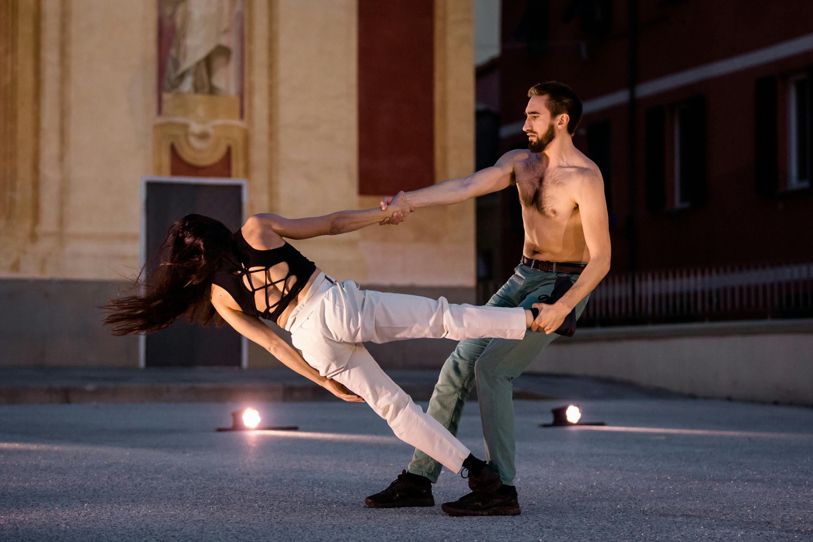 Un danzatore sostiene da un braccio una danzatrice in fuori peso